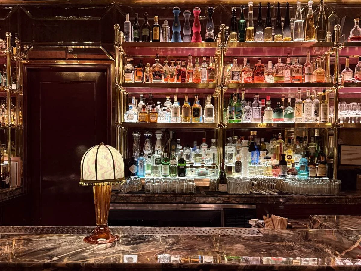 Glowing brass spirit shelves and marble counter at Titsou Bar speakeasy inside Fouquet's New York
