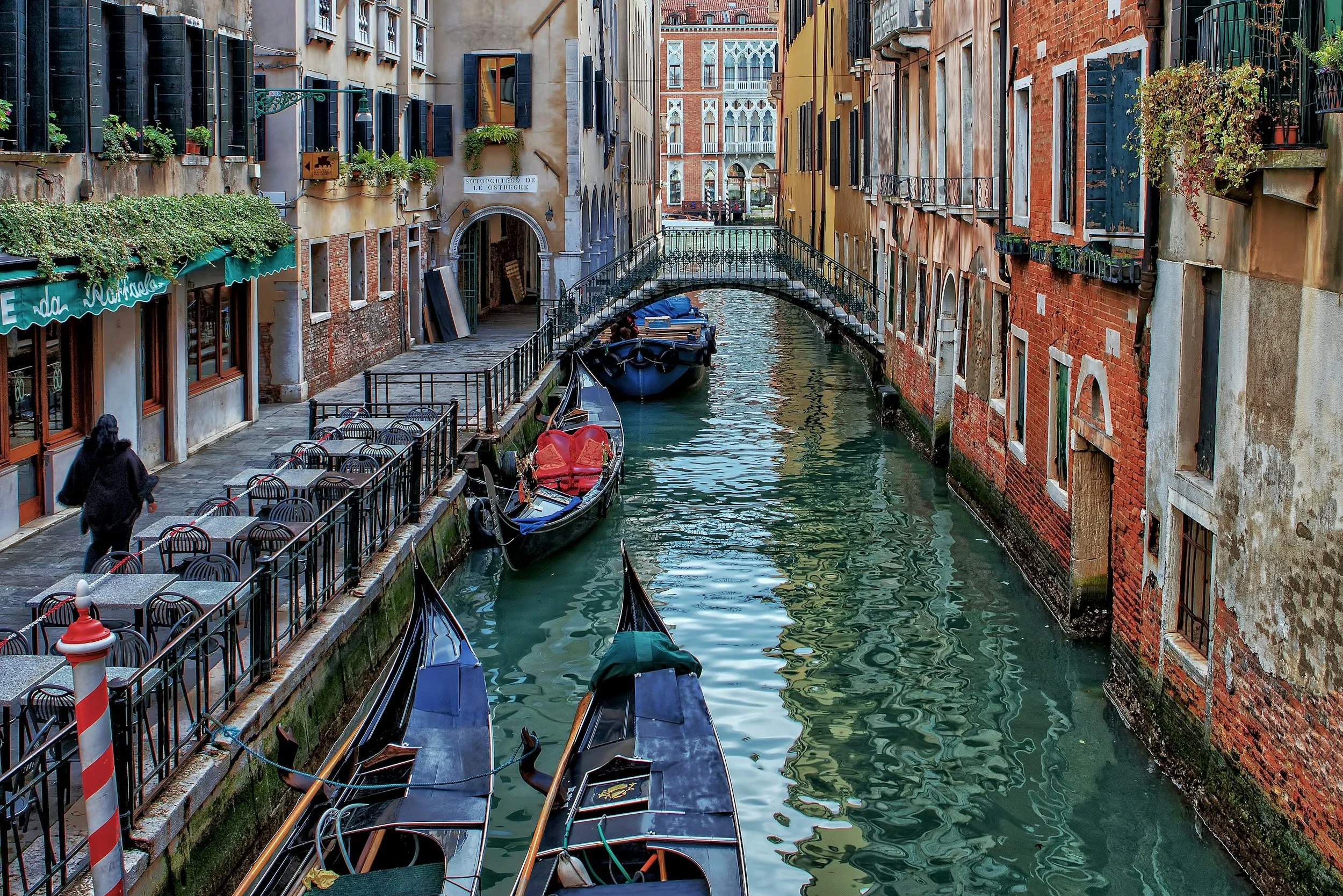 Gondolas moored along a quiet side canal lined with shuttered palazzi, Venice, Italy