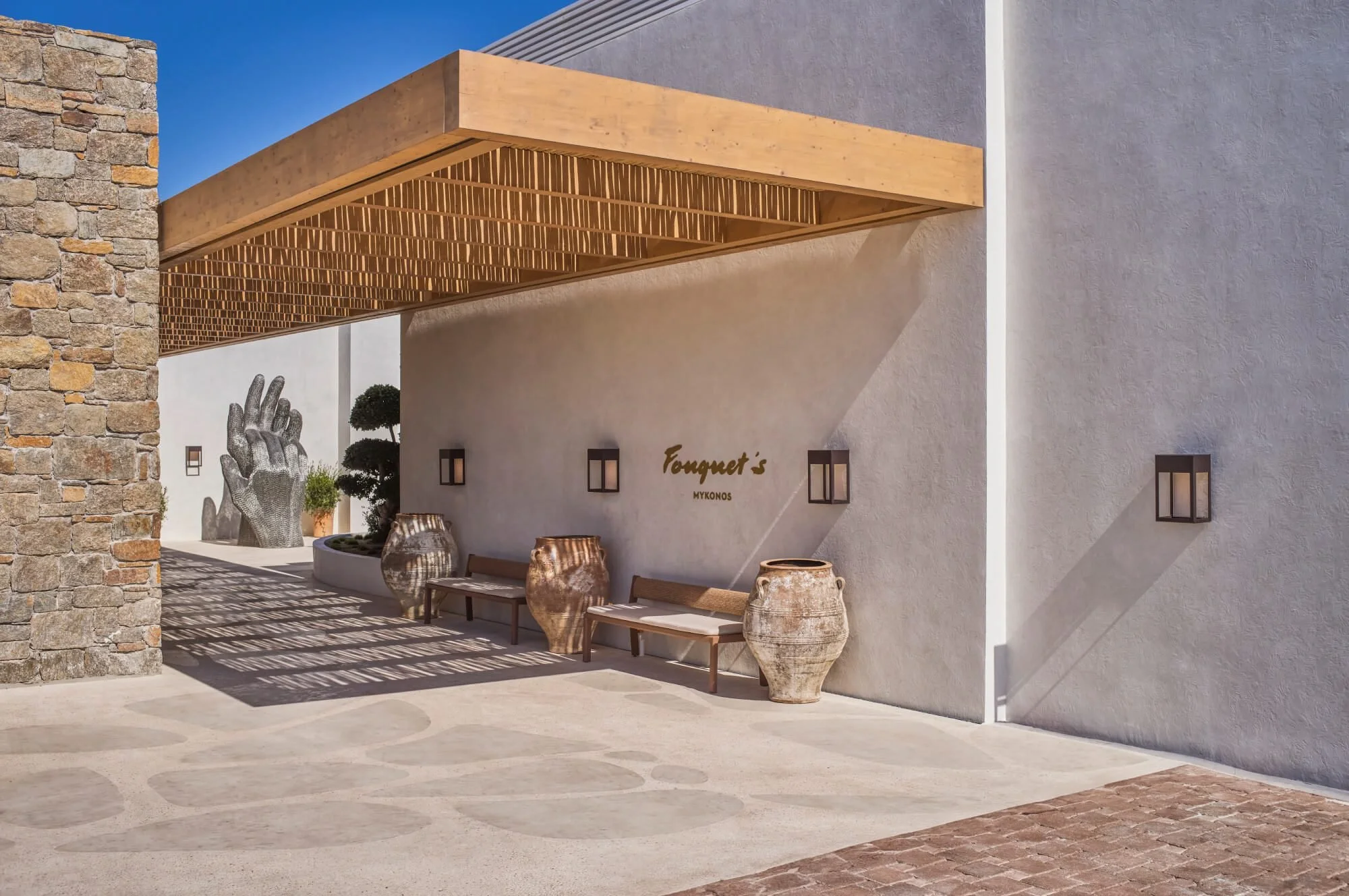 Entrance courtyard at Fouquet's Mykonos with sculpture and Greek urns near Paraga Beach
