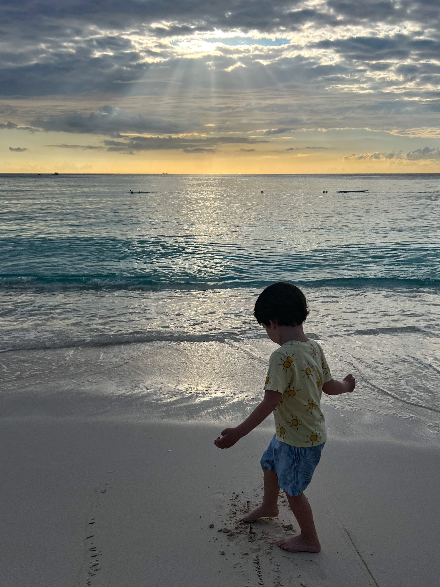 boy playing in the sand on seven mile beach at sunset