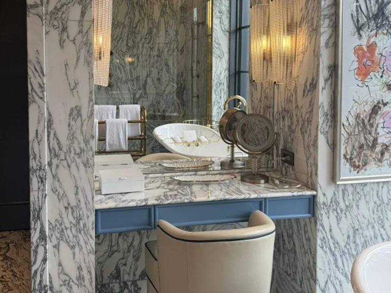 Calacatta marble bathroom vanity with blue accents and plush chair at Fouquet's New York