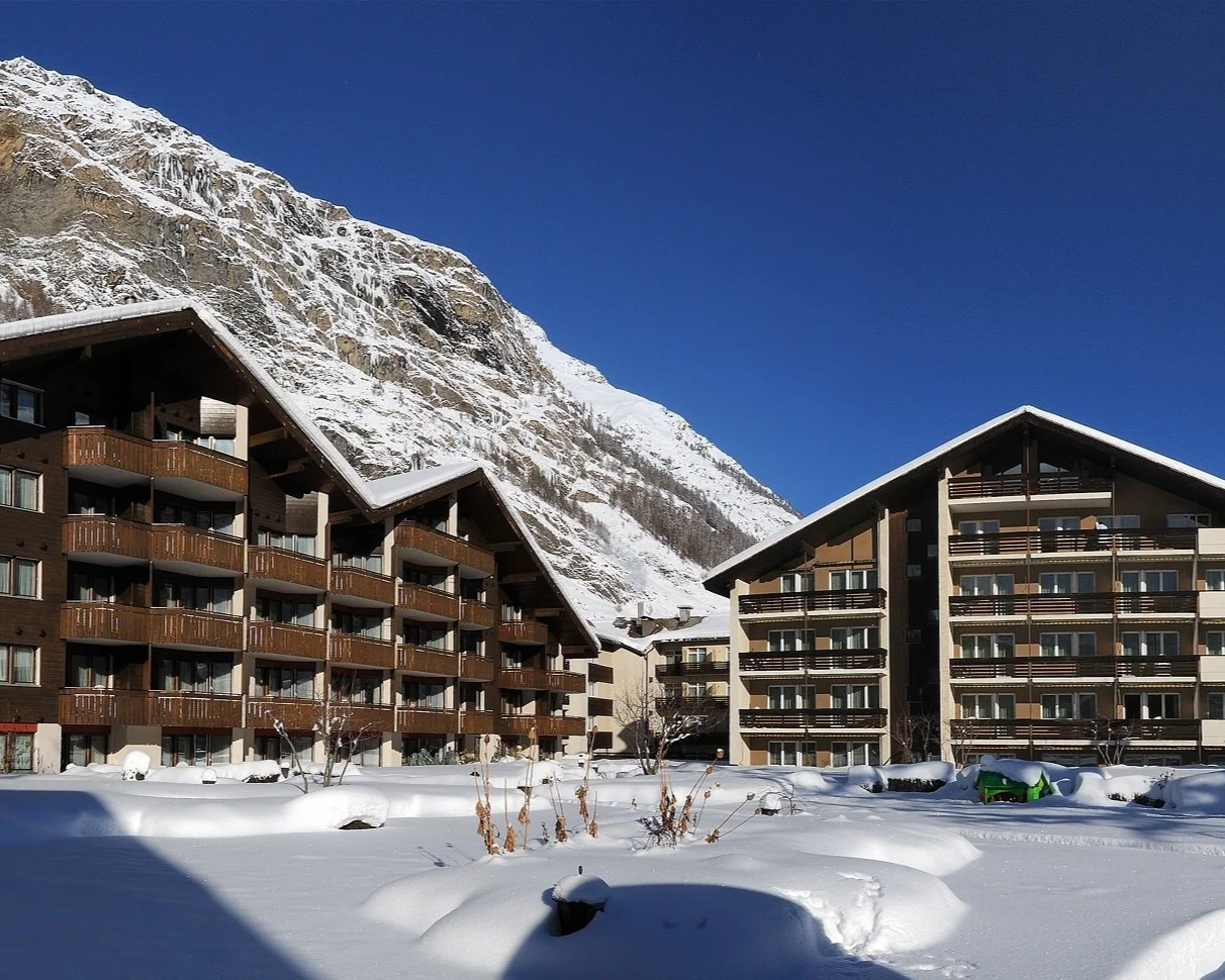Schweizerhof Zermatt chalet-style hotel exterior in deep winter snow with mountain backdrop