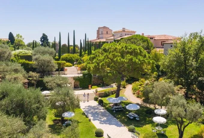 Terraced Mediterranean gardens and white umbrella-shaded walking paths leading up to Château Saint-Martin & Spa in Vence.