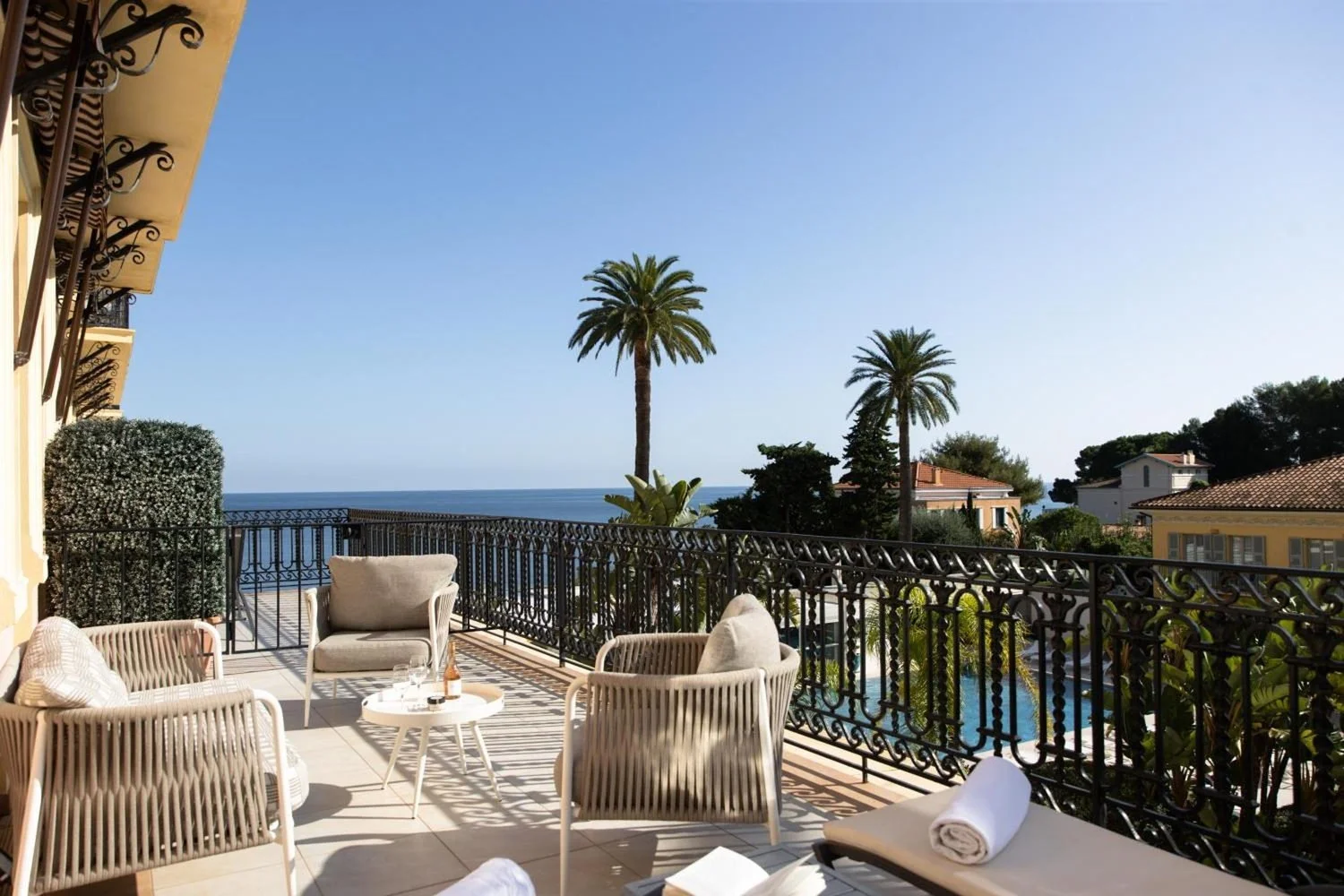 Suite terrace with wrought-iron railing looking over palms to the sea, Royal-Riviera, Cap-Ferrat