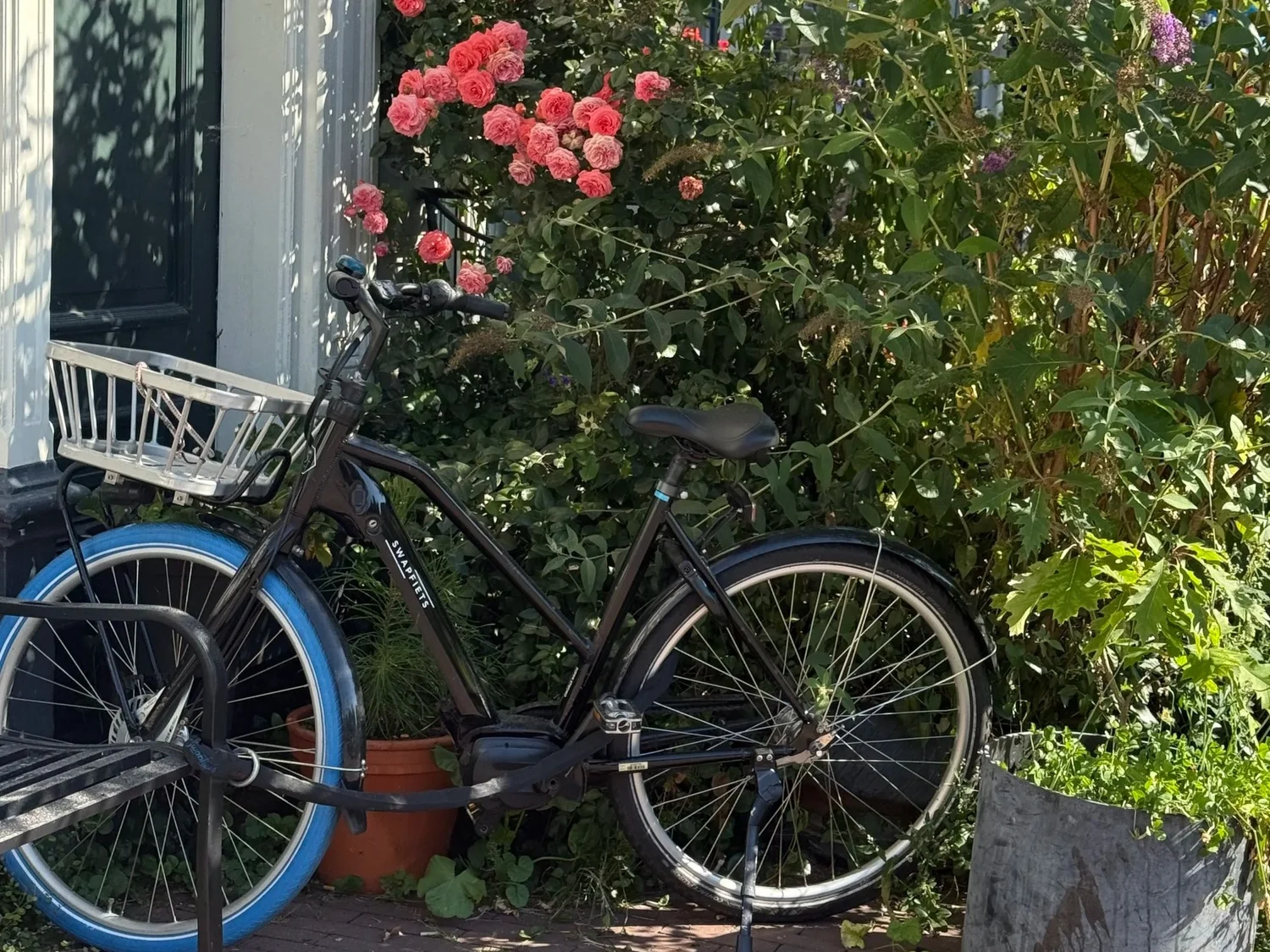 A bicycle outside a canal house with flowers in Amsterdam