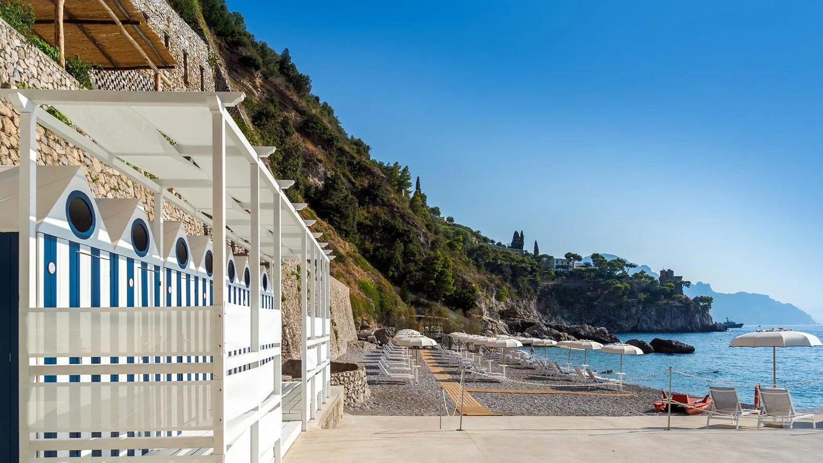 Blue and white striped changing cabins and loungers at the Marinella Beach Club at Borgo Santandrea