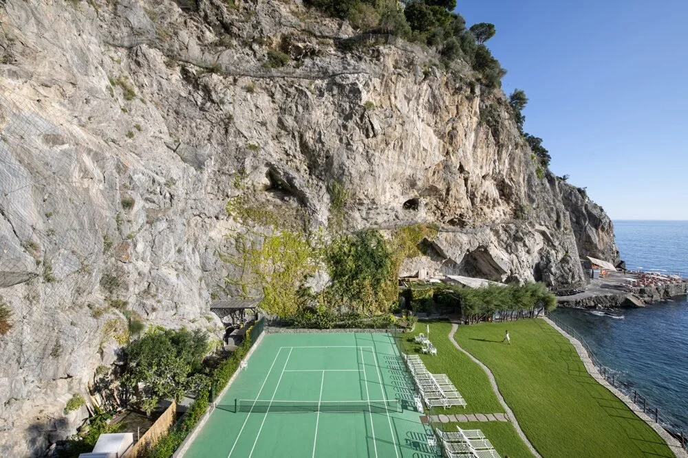 Seaside tennis court at Il San Pietro di Positano between the limestone cliff and the Mediterranean