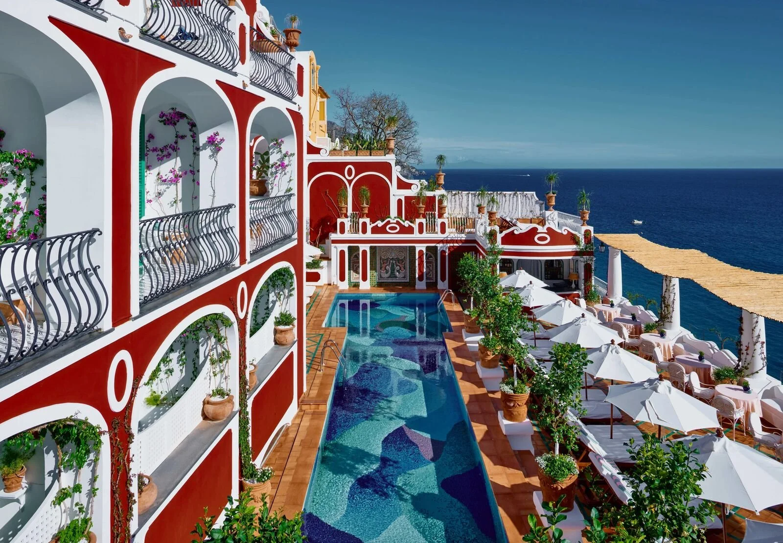 Red facade of Le Sirenuse above Positano with the tiled dome of Santa Maria Assunta and Spiaggia Grande