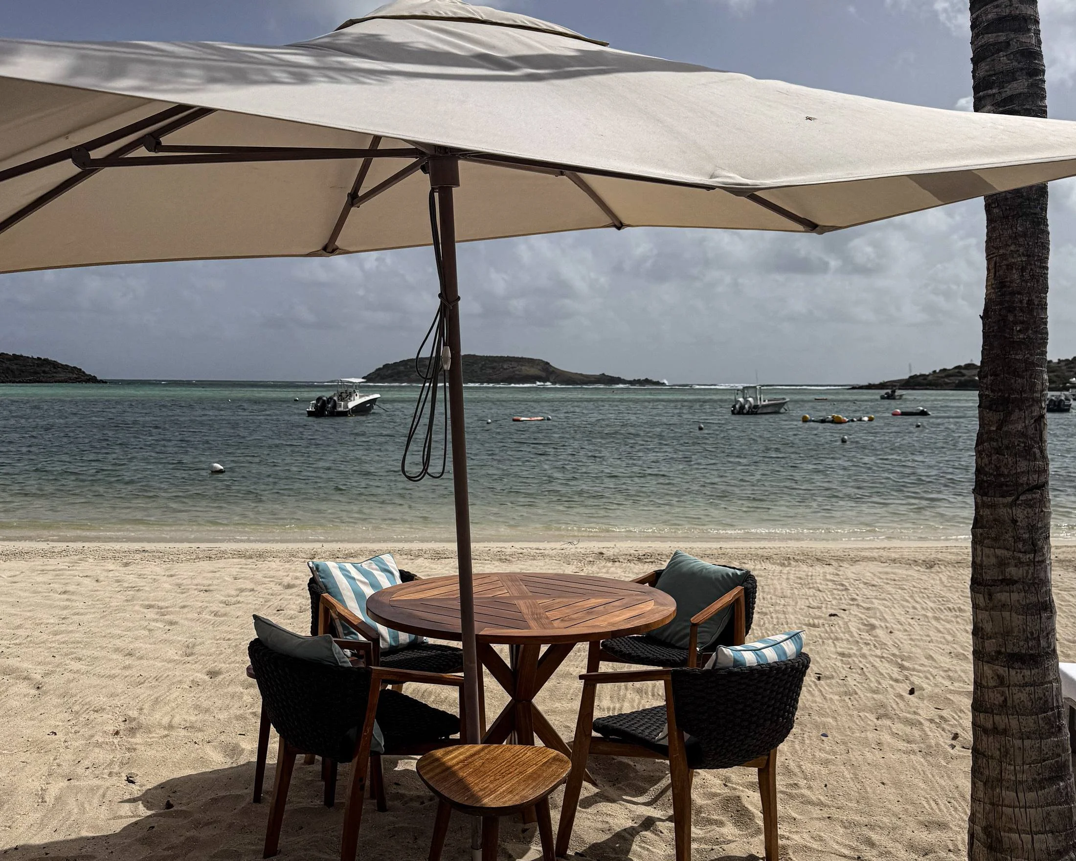 Beach table under a parasol on the calm Grand Cul-de-Sac lagoon at Le Barthélemy St. Barth