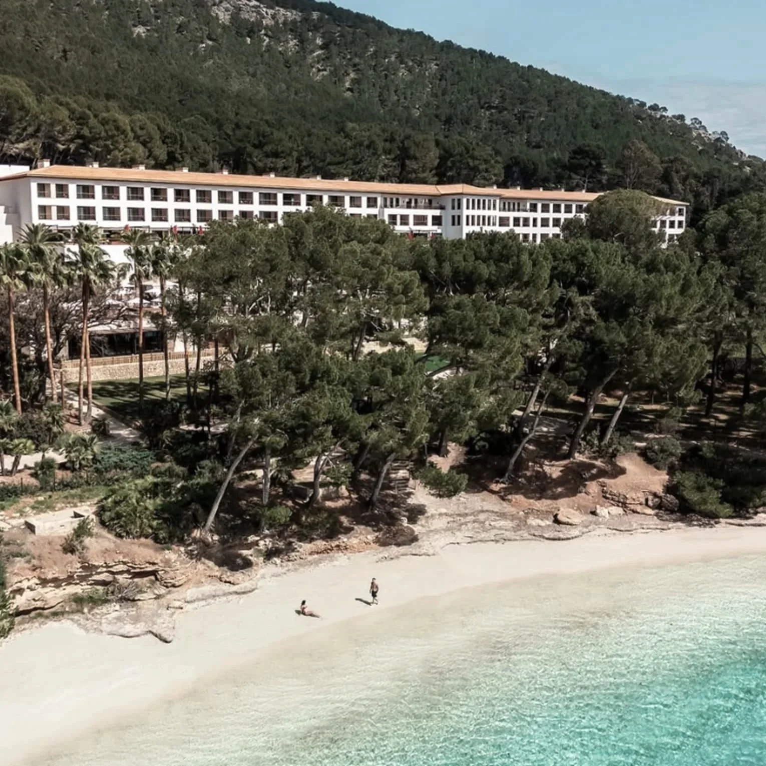 Aerial view of Four Seasons Resort Mallorca at Formentor above a pine-backed beach and clear turquoise water on Mallorca's north coast