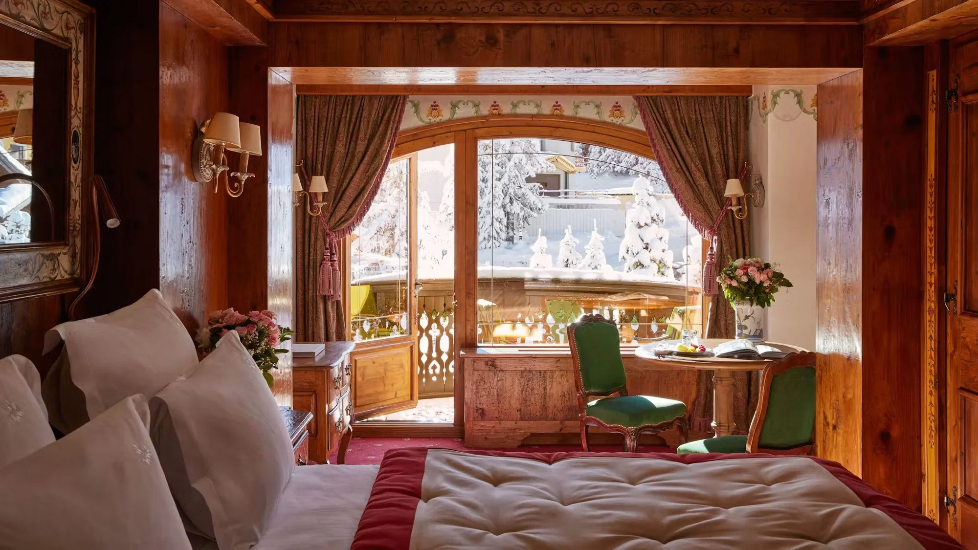 Deluxe room at Airelles Courchevel with painted panels, antiques and a balcony onto the pines.