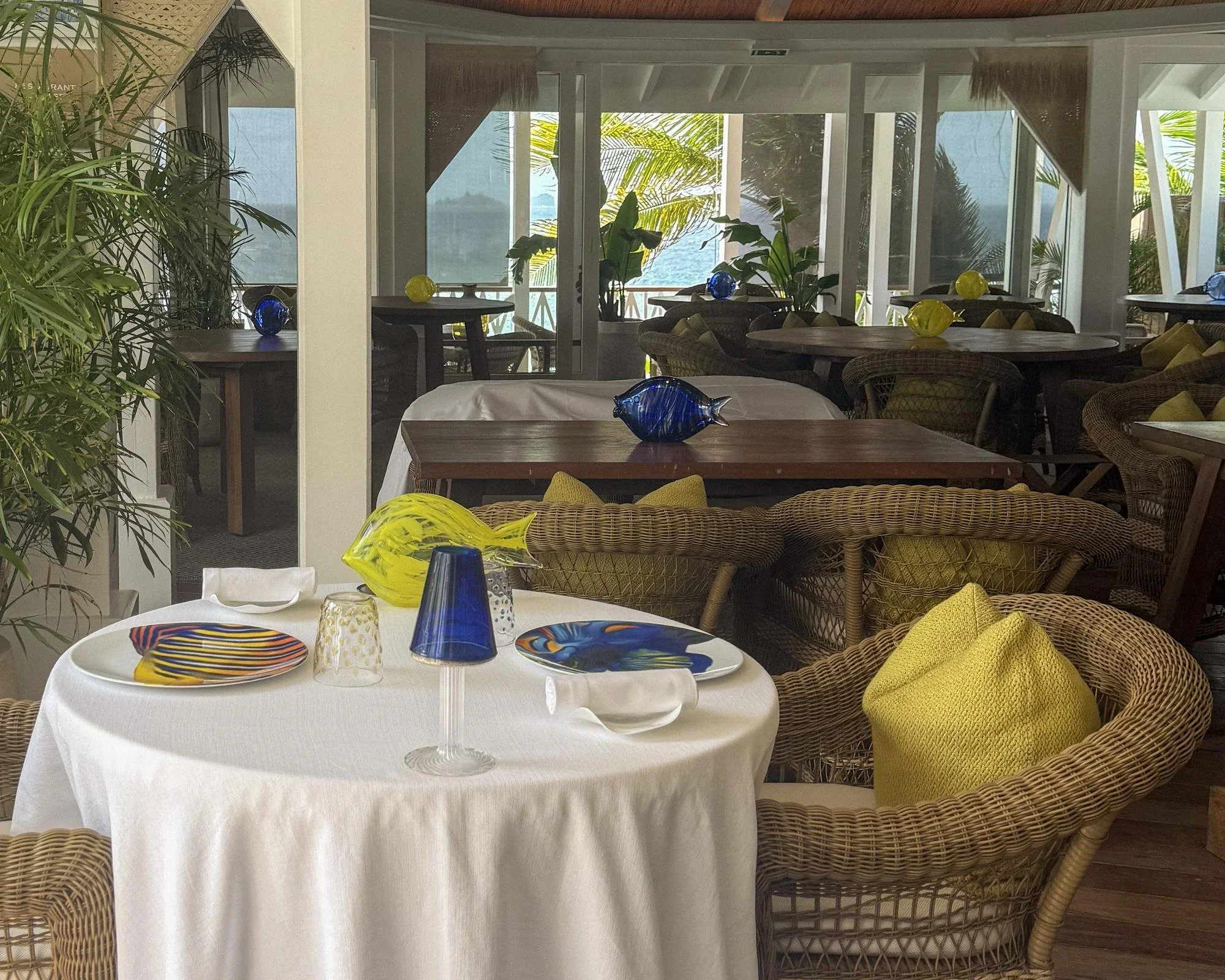 Table set with hand-painted fish plates and blown glass fish at a restaurant at Cheval Blanc St-Barth