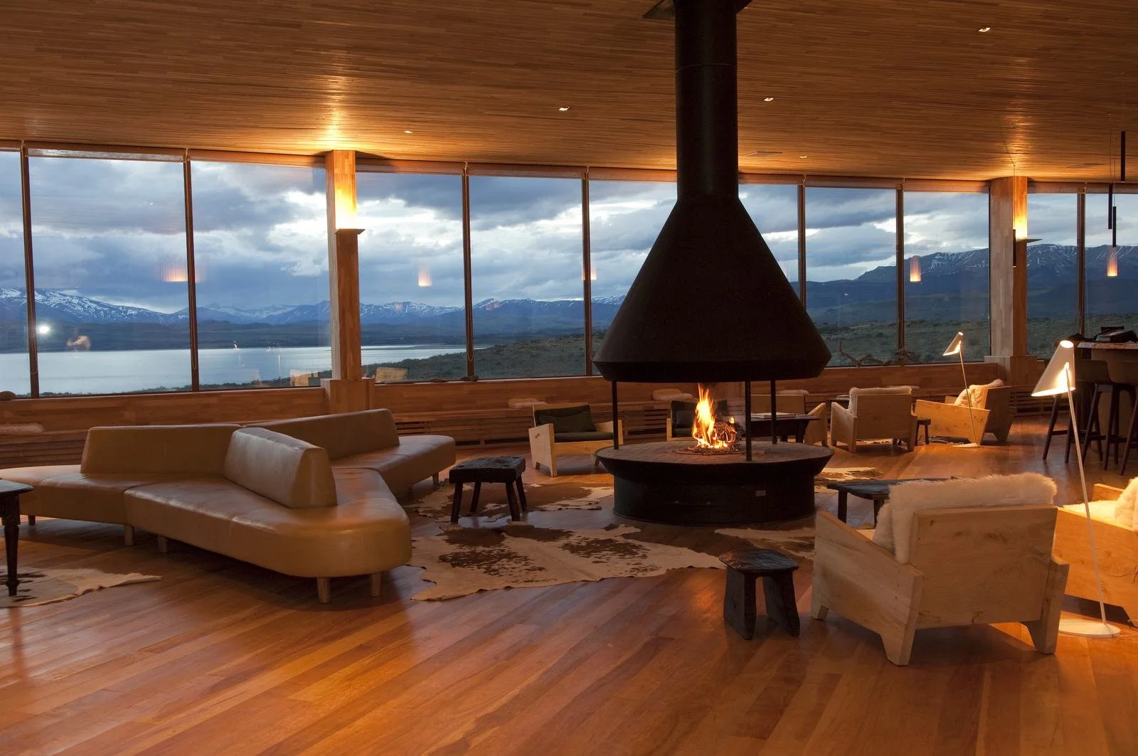 Suspended conical fireplace in the main lounge at Tierra Patagonia with windows onto Lake Sarmiento