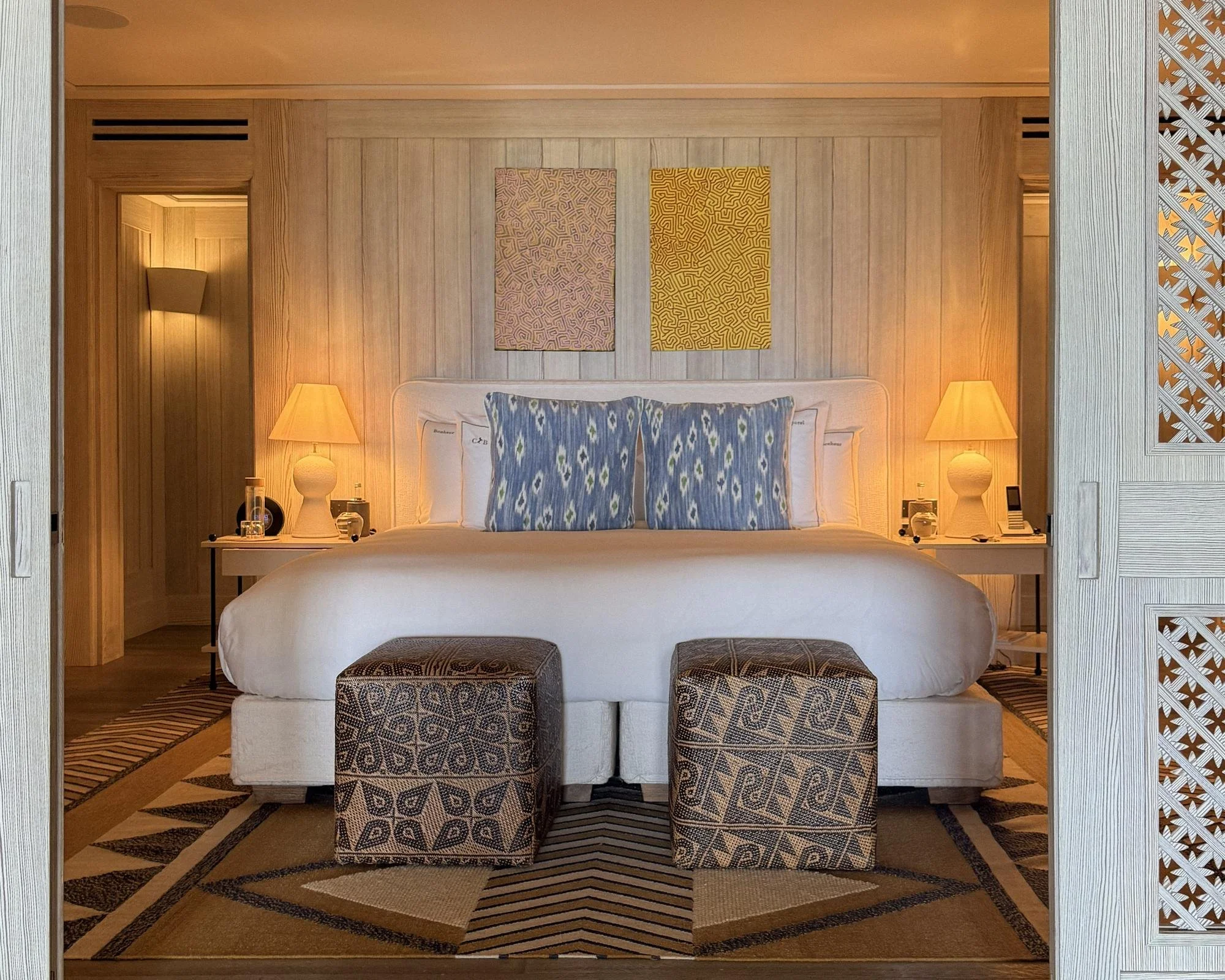 Guest room at Cheval Blanc St-Barth with ikat cushions, patterned ottomans and whitewashed wood screens