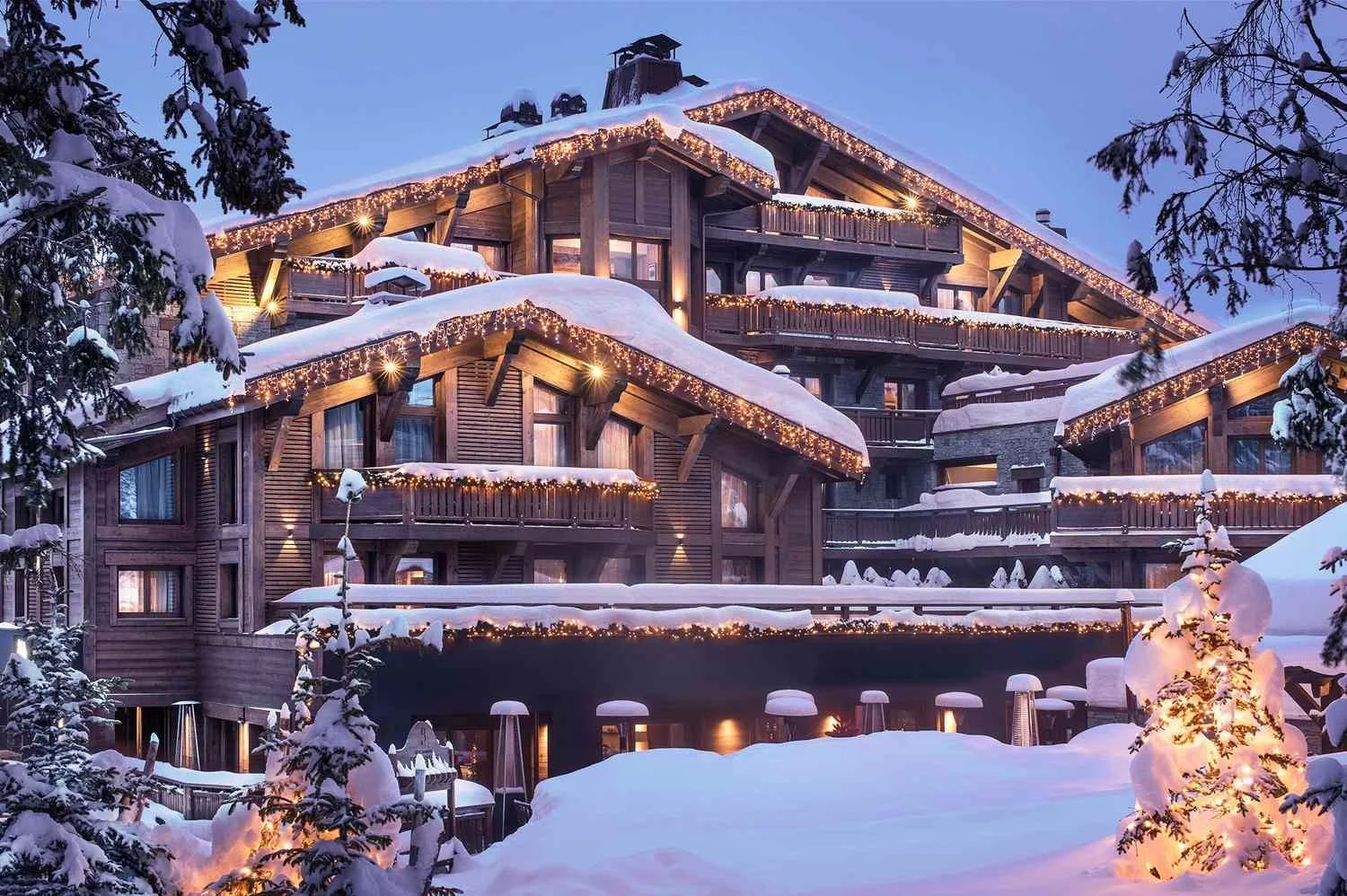Exterior del Fouquet’s de Courchevel al atardecer, cubierto de nieve, en la pista de Bellecôte.