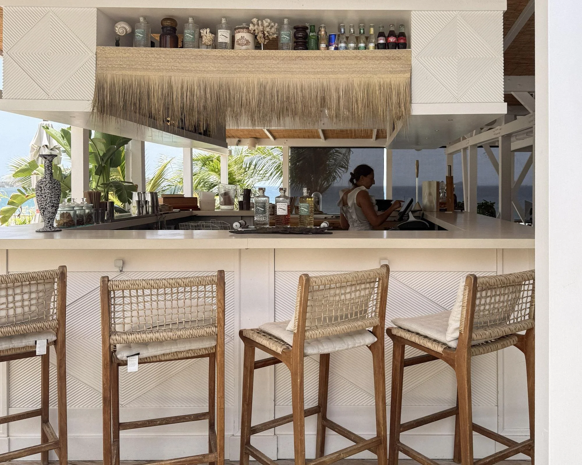 Woven bar stools and Eminente rum bottles at the open-air bar at Cheval Blanc St-Barth