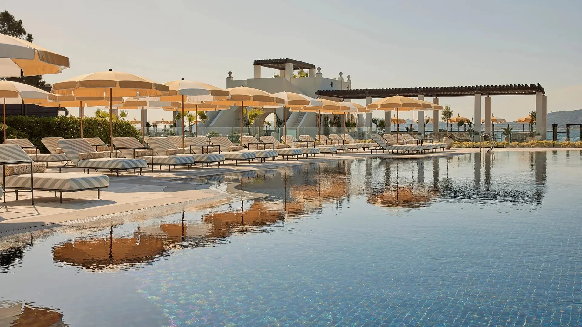 Mosaic-tiled 25-meter swimming pool surrounded by palm trees and gardens at COMO Le Beauvallon