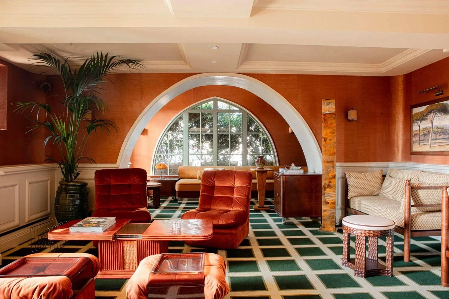 Terracotta lounge with arched window and velvet chairs at Mas Candille in Mougins
