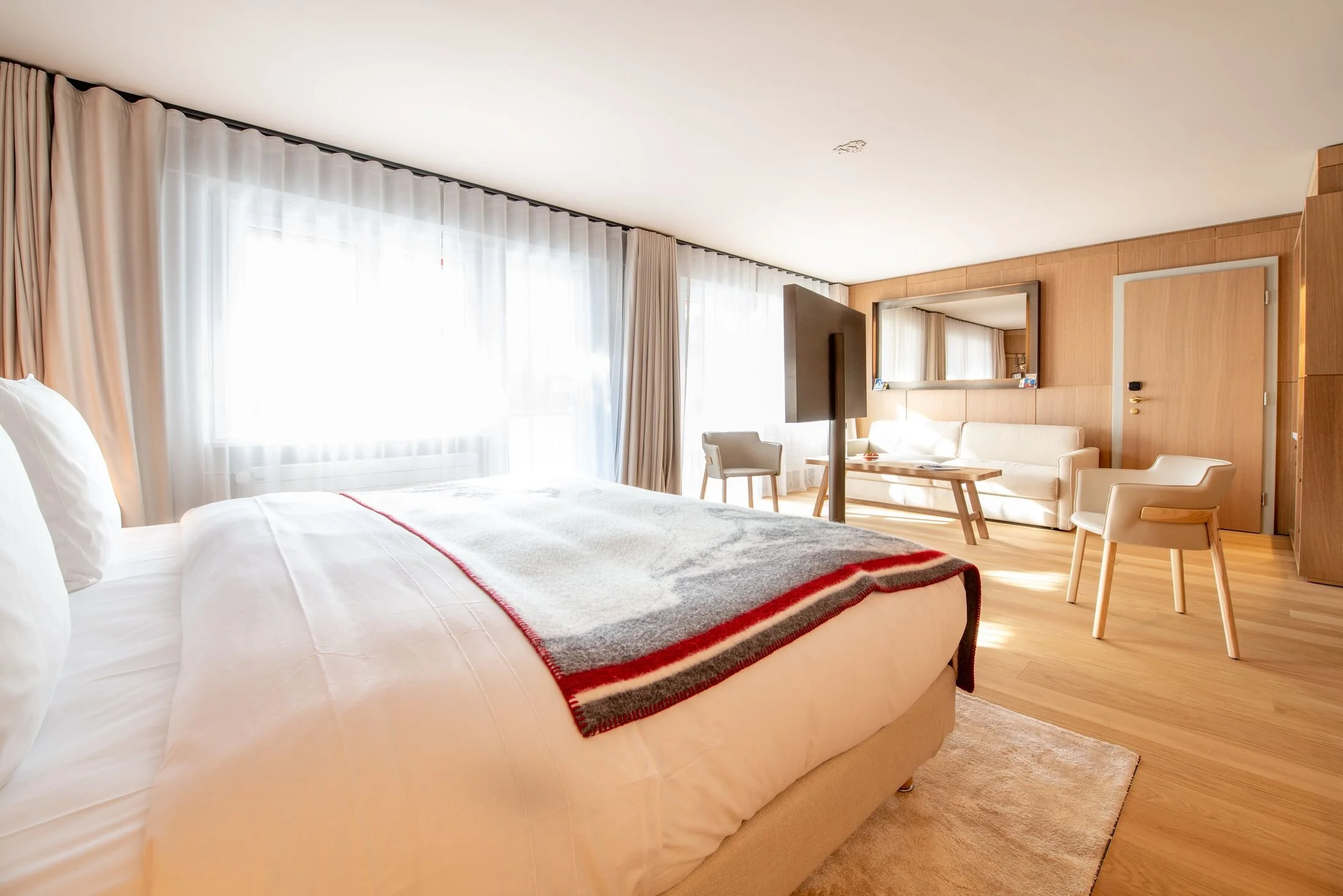 Junior Suite bedroom with king bed, sofa bed, and modern Alpine decor at Schweizerhof Zermatt