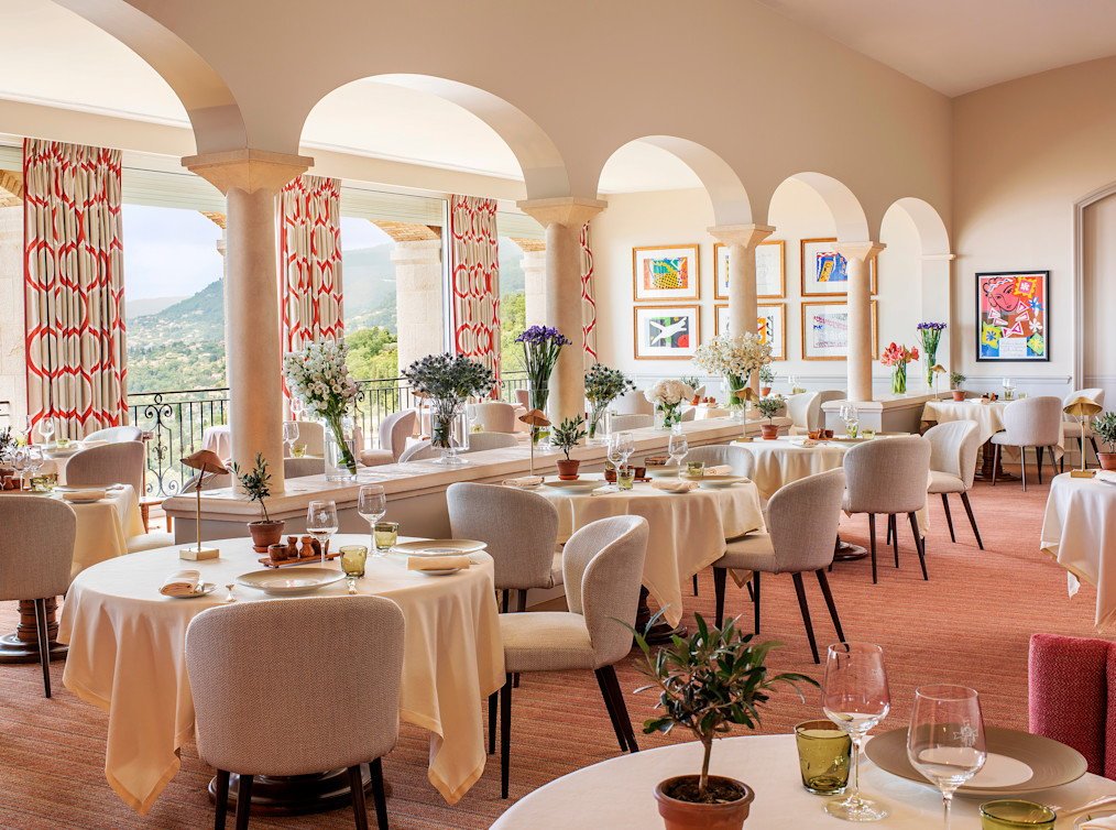 Arched dining room with white linen and sea-facing windows at Le Saint-Martin, Vence