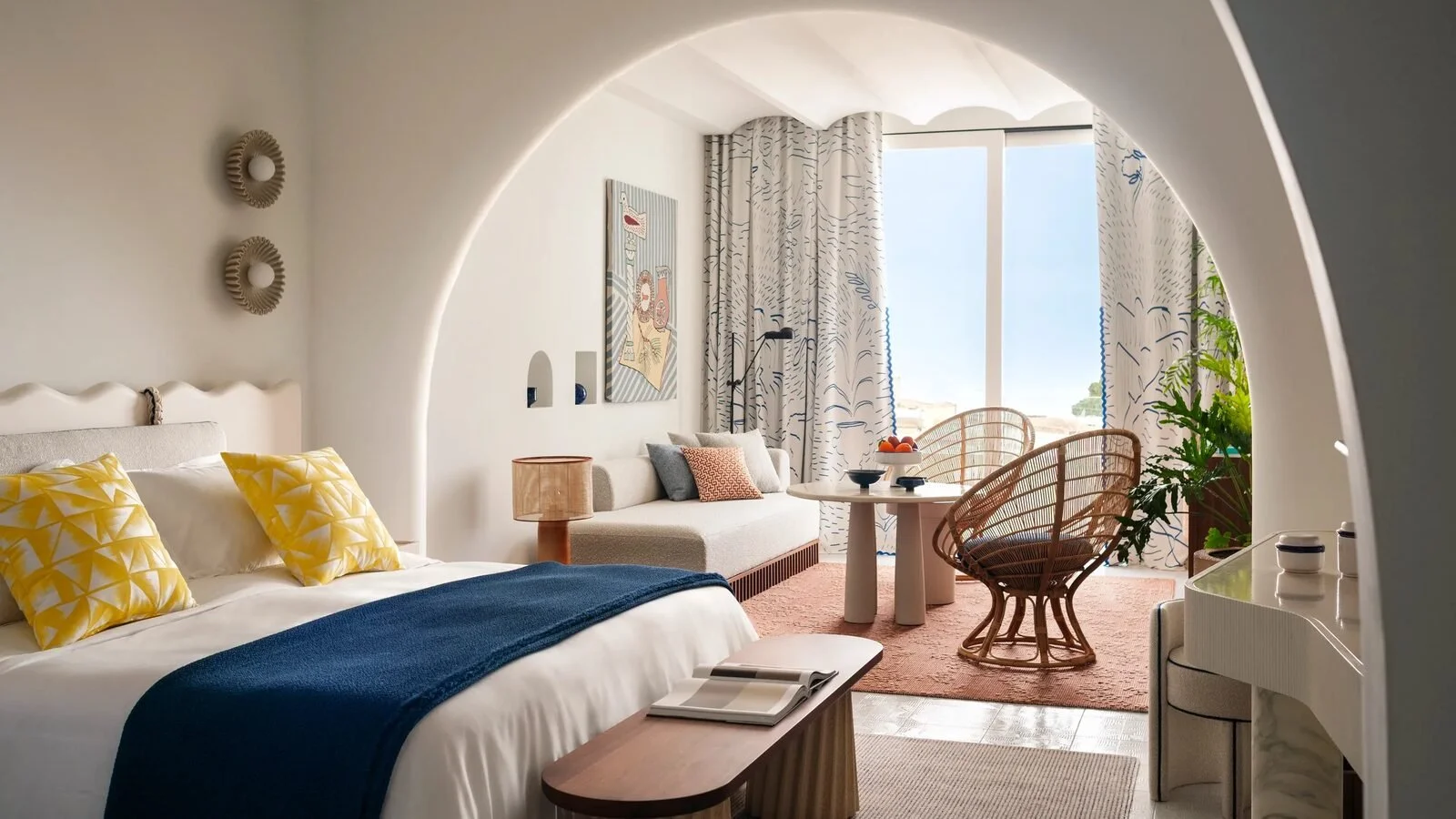 Suite bedroom designed by Patricia Urquiola at Jumeirah Capri Palace with a vaulted arch, rattan chairs and printed curtains