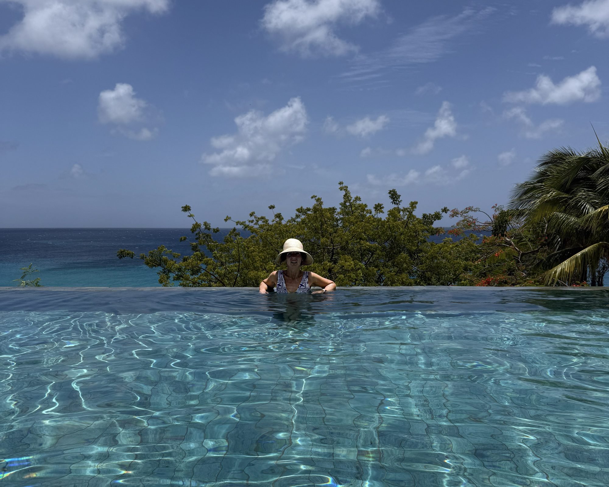 Author Kate Van Dell in a sun hat in the infinity pool overlooking the sea at Malliouhana Anguilla