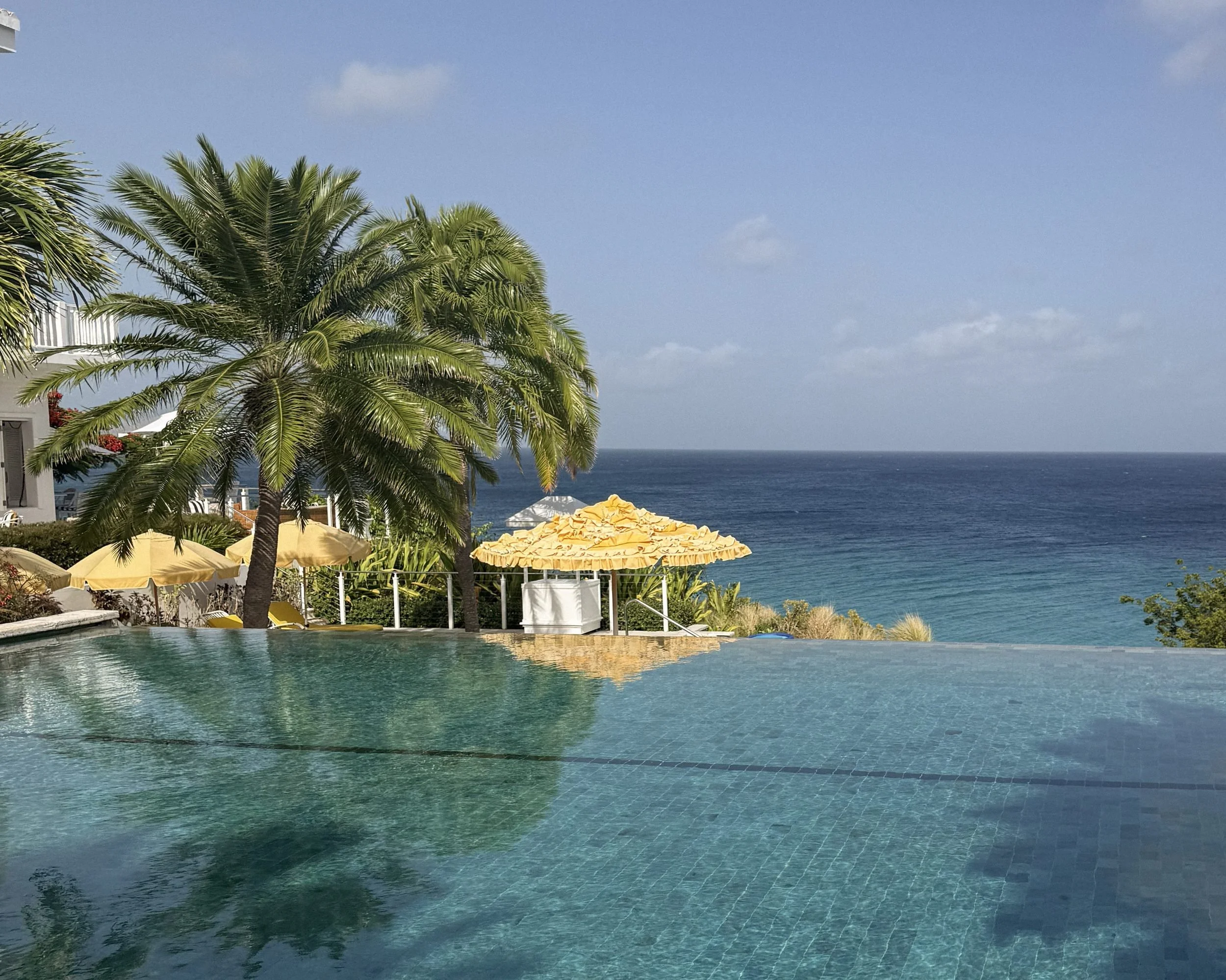 nfinity pool with palm and yellow umbrella overlooking the ocean at Malliouhana Anguilla