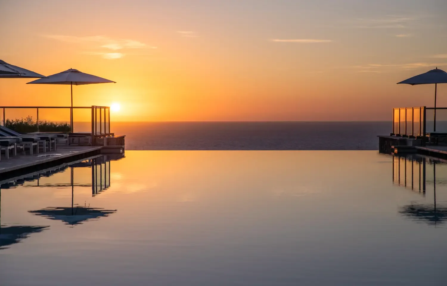 Infinity pool overlooking the Mediterranean Sea at sunset, with sun loungers and umbrellas at Jumeirah Mallorca in Port de Sóller.