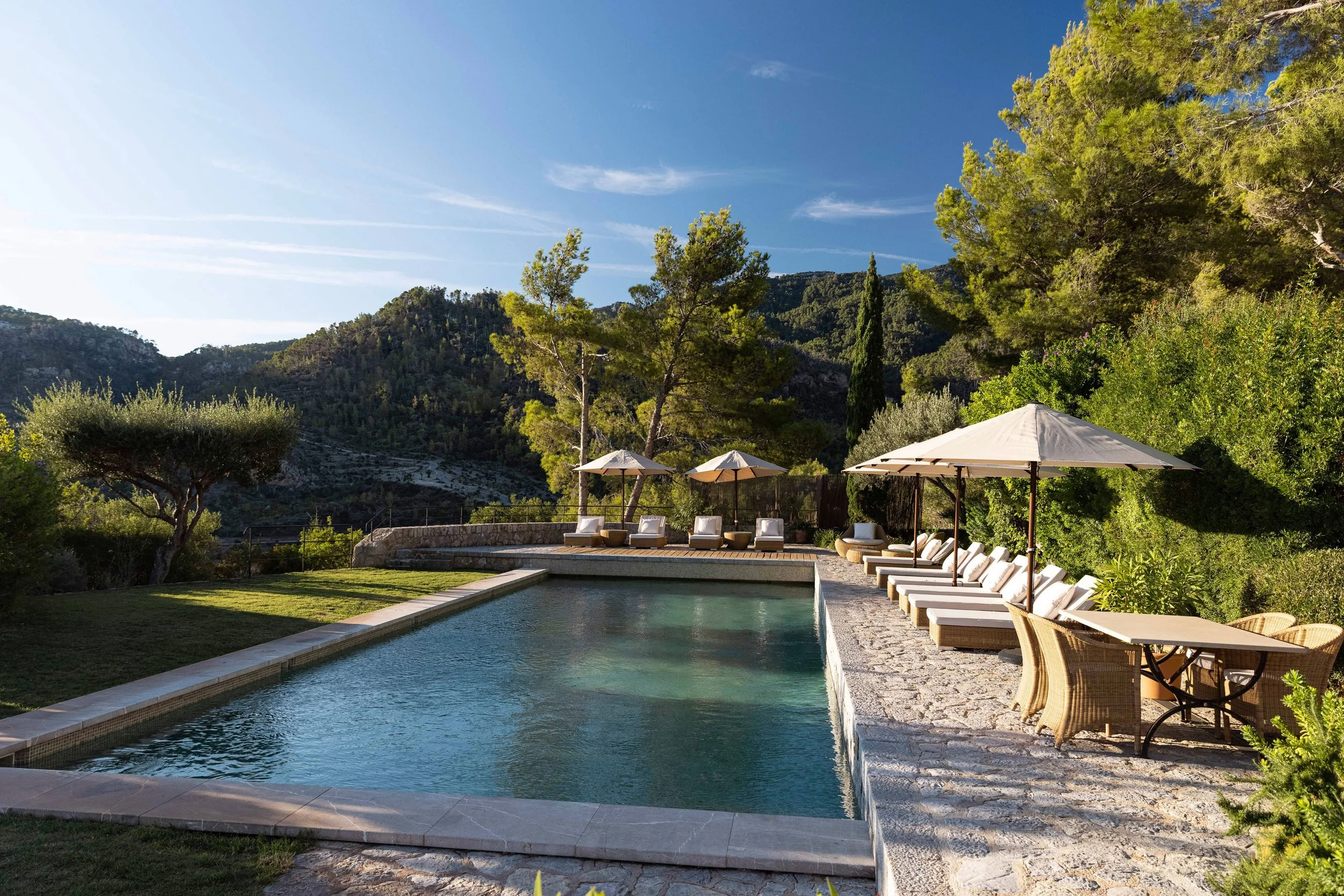 Private villa pool at Son Bunyola's Sa Punta de S'Aguila in Mallorca, a long pool flanked by loungers and parasols beneath the Tramuntana mountains.