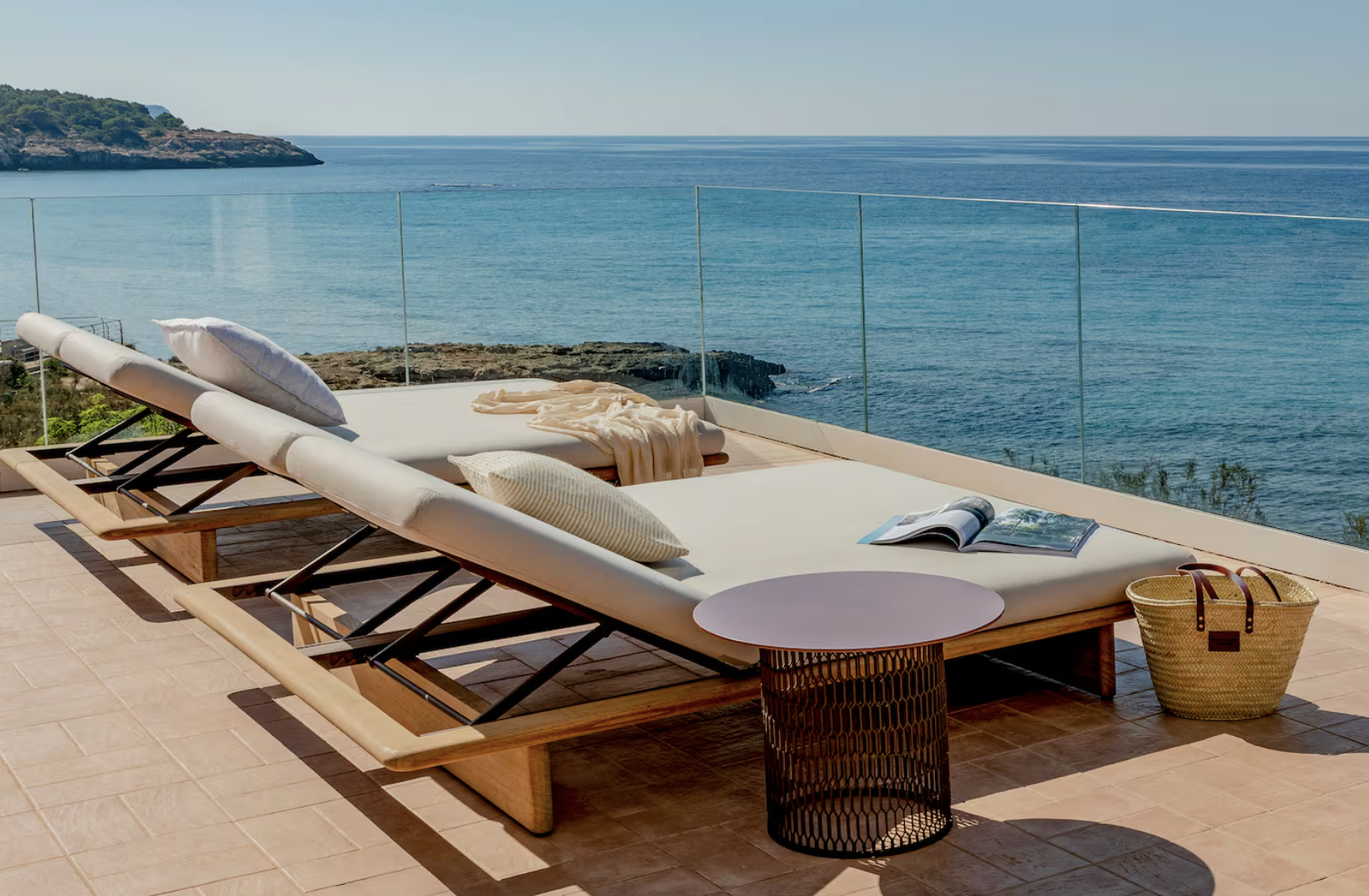 Two cushioned sun loungers on a tiled terrace overlooking the Mediterranean Sea at Villa Le Blanc in Santo Tomás, Menorca.