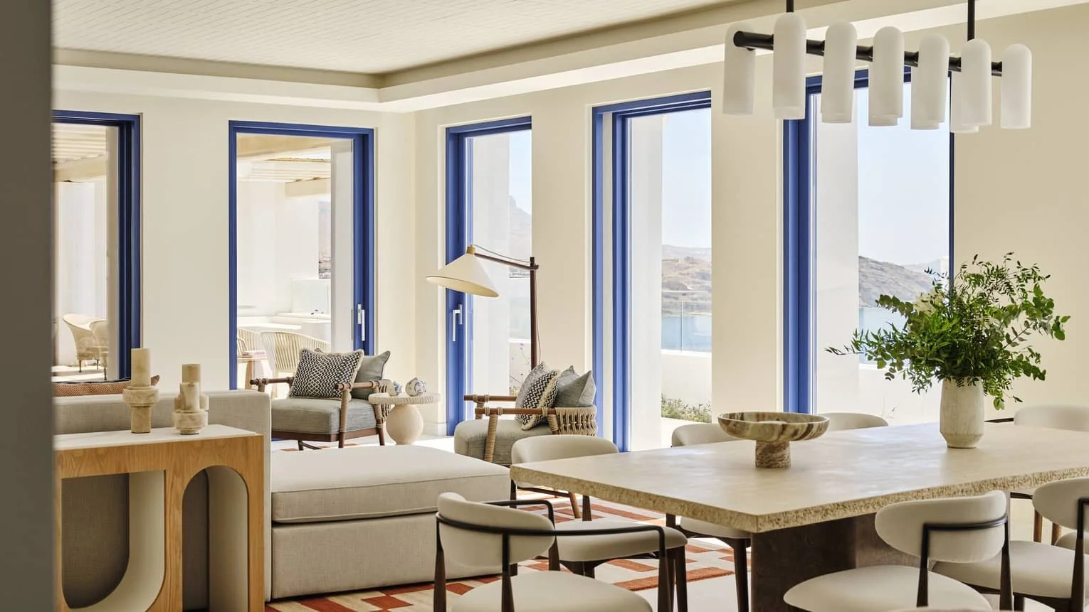 Living and dining room with blue window frames and sea views at Four Seasons Hotel Mykonos