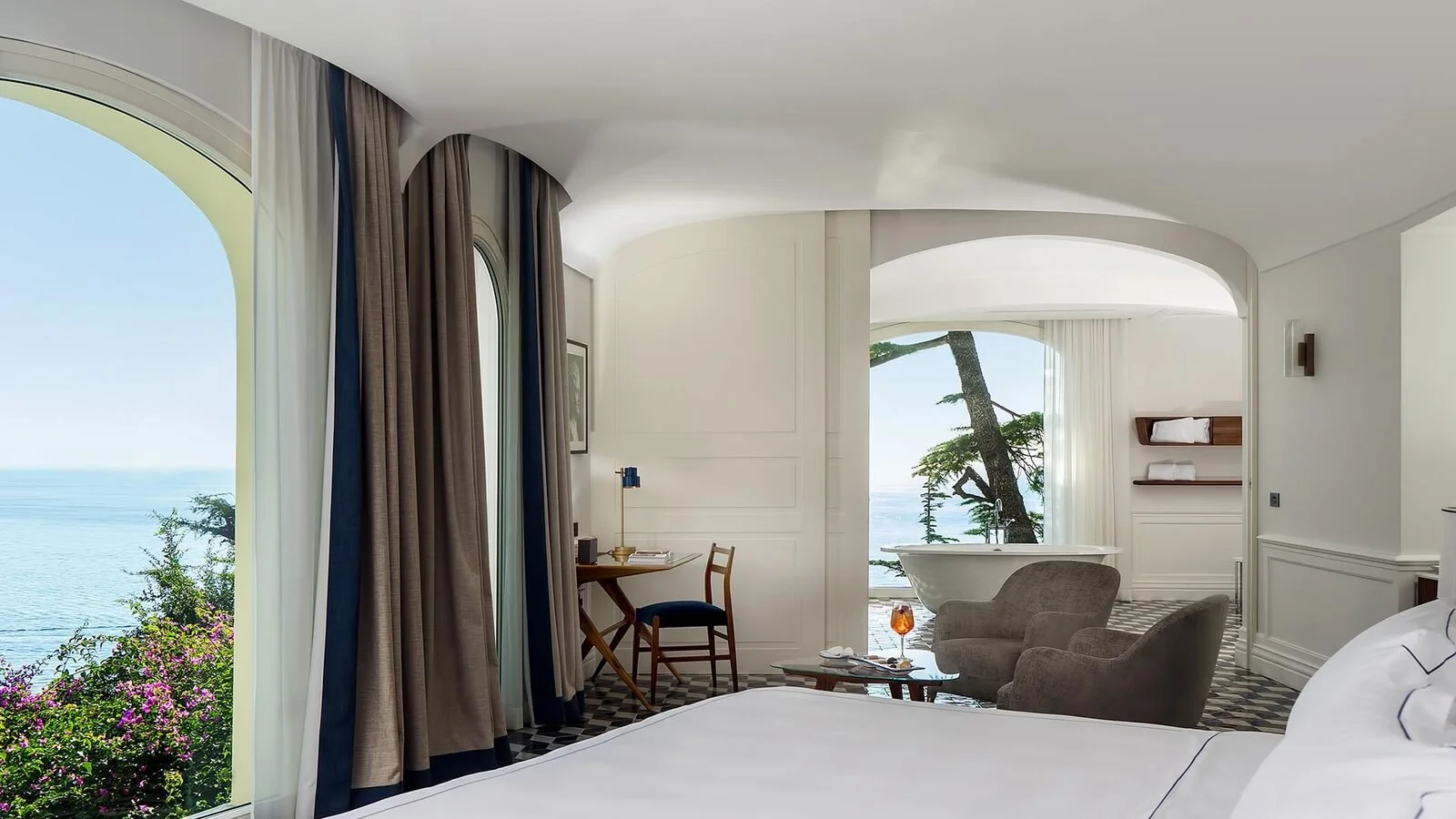 Suite bedroom at Borgo Santandrea with a freestanding bath in an adjoining arched room facing the sea