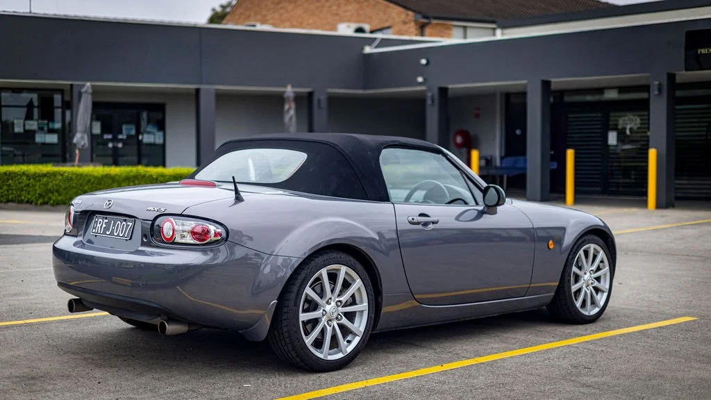 A gray Mazda MX-5 Miata convertible sports car parked in a parking lot