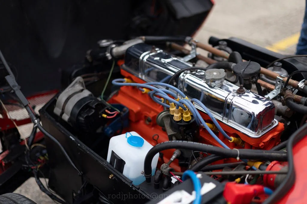 Close-up of a car engine with chrome and orange components, blue and yellow wires, and a white coolant reservoir.
