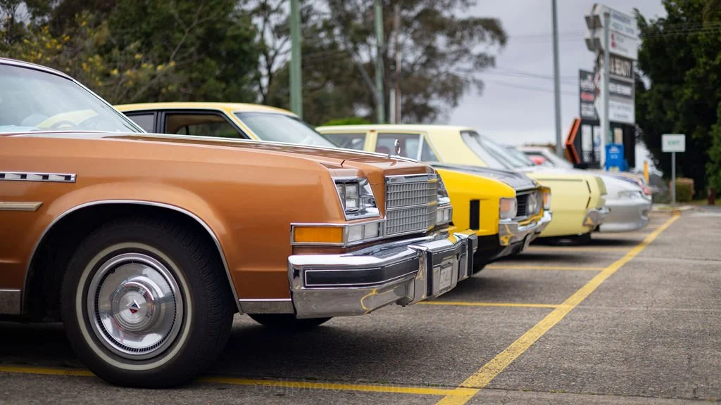 A line of vintage cars parked in a parking lot.