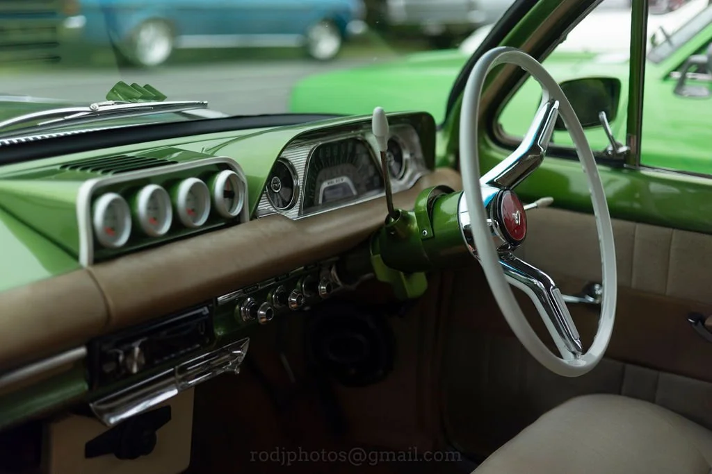 Interior of a vintage green car with a beige dashboard and steering wheel.