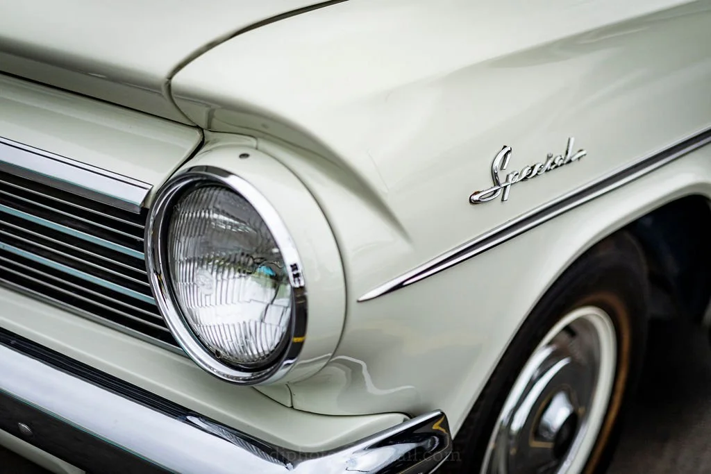Close-up of a vintage white Studebaker car with a round headlight and chrome details.