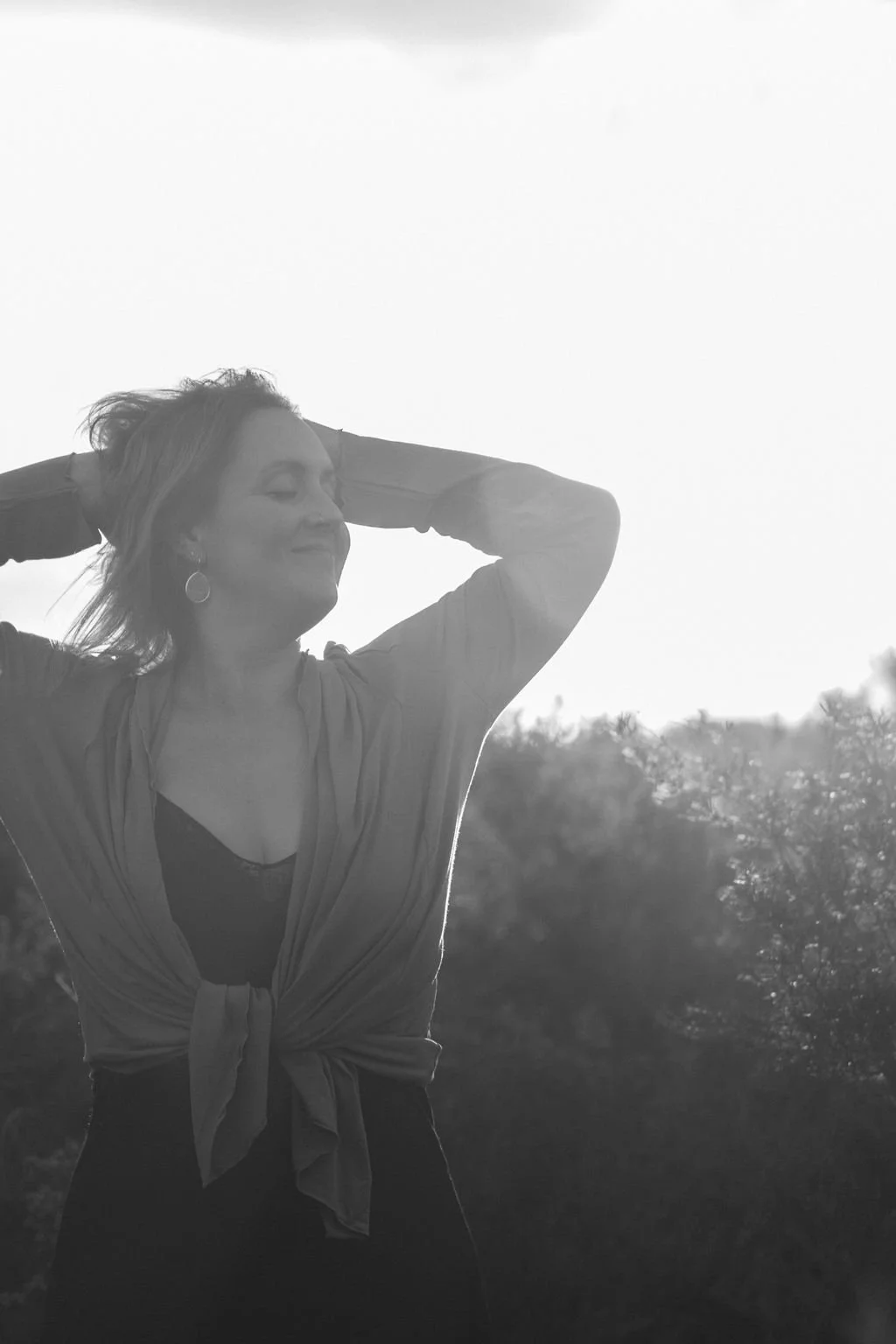 Wild & Sacred Feminine Embodiment Coaching black & white photo of Camilla smiling with her arms raised