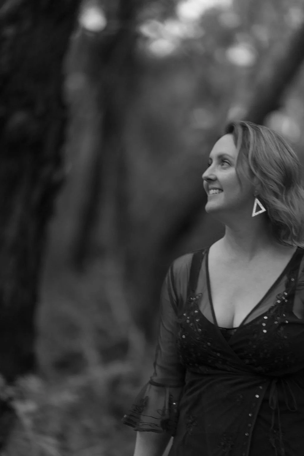 Wild & Sacred Feminine Embodiment Coaching black & white photo of Camilla smiling in the bush looking to the side