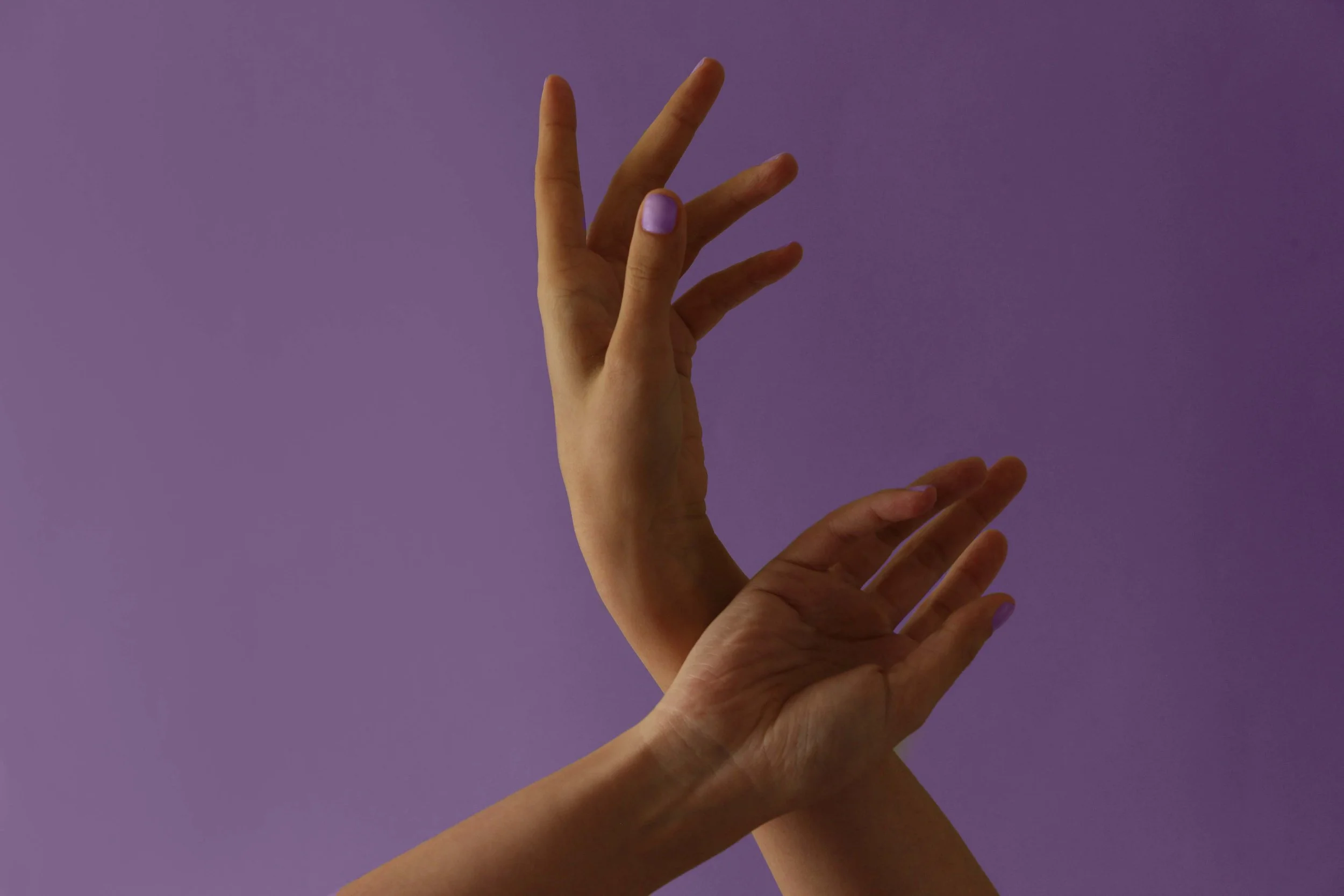 Wild & Sacred Feminine Embodiment Coaching photo of a womans hands raised in the air in front of a deep purple backdrop