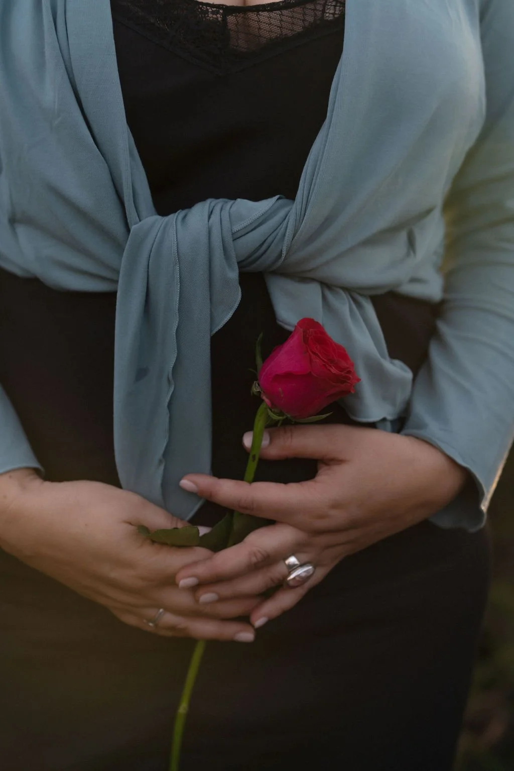 Wild & Sacred Feminine Embodiment Coaching photo of Camilla holding a red rose in front of her wombspace