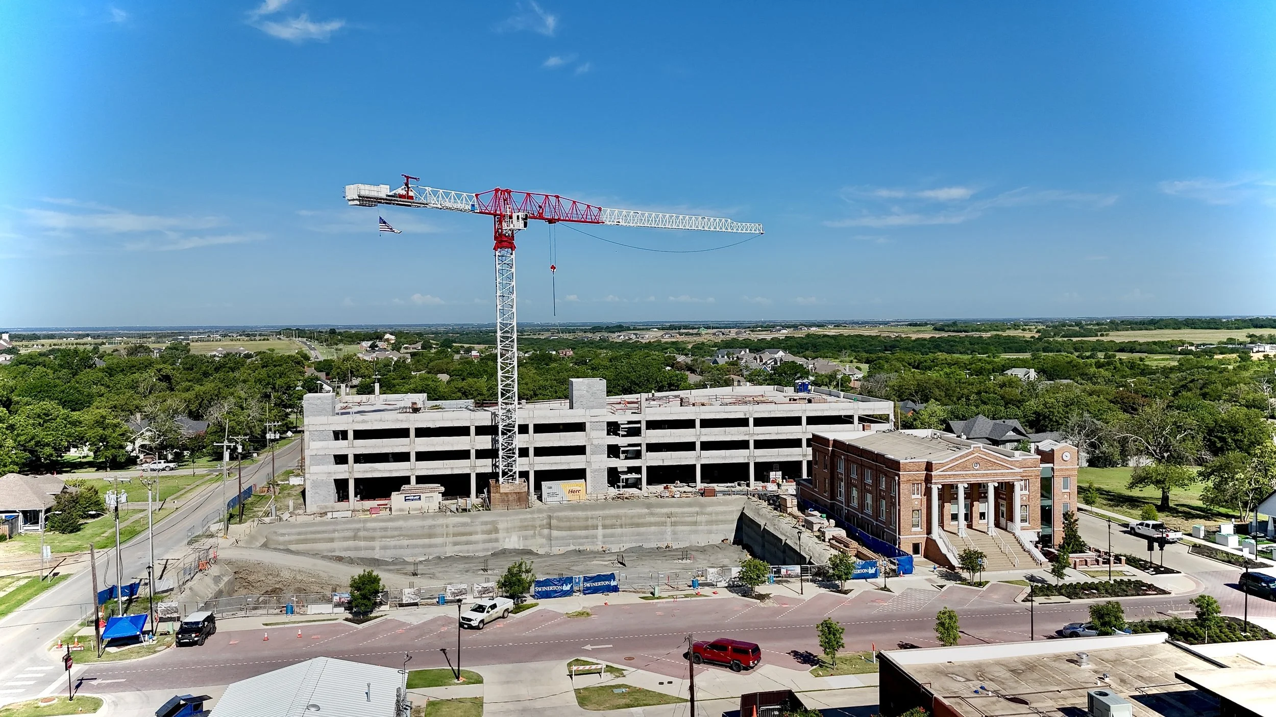 Aerial view of a construction site with a large crane and adjacent residential area.