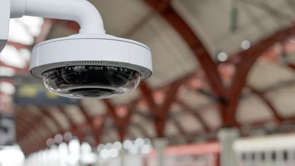 Close-up of a security camera hanging from a ceiling in a train station