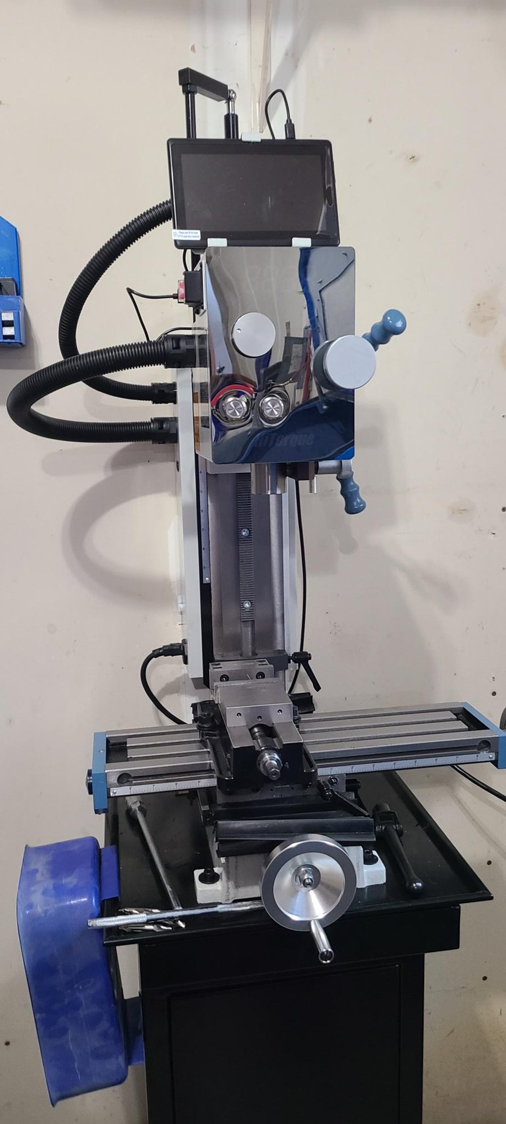 Vertical milling machine with control panel and hand wheels in a workshop setting.