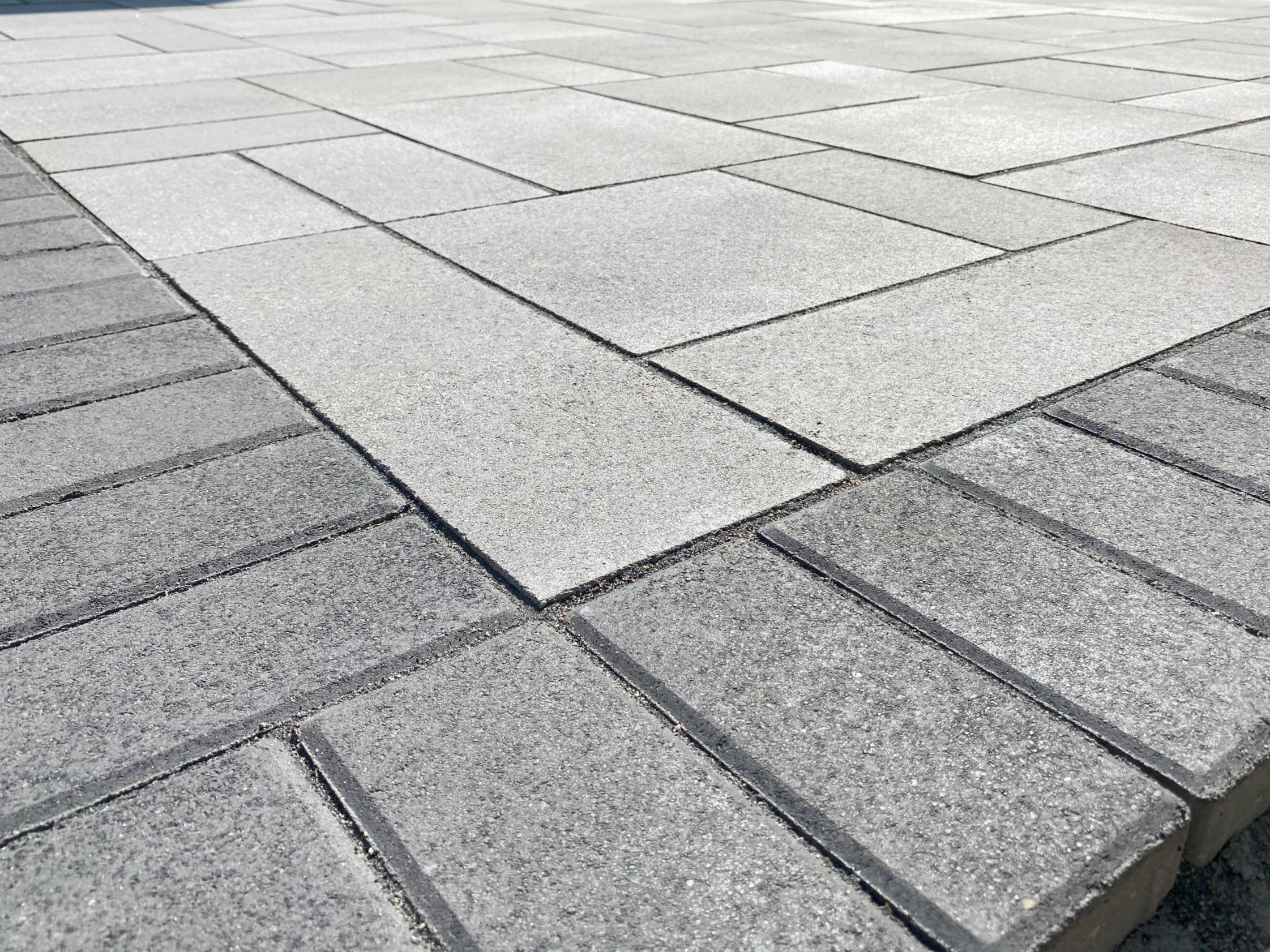 Close-up of an outdoor paver patio with Unilock umbriano rectangular concrete pavers in light gray and dark gray colors.