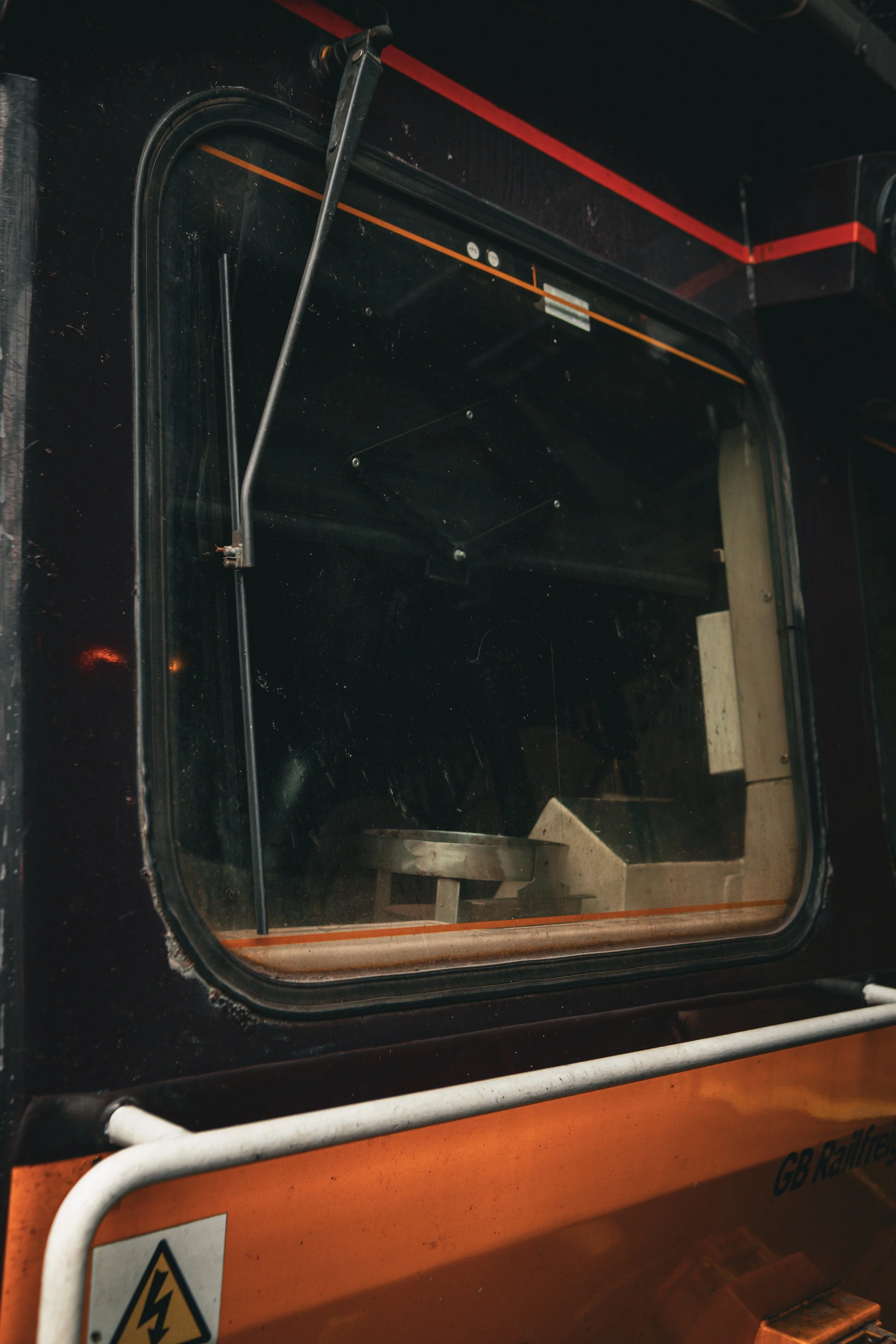 View inside a black and orange shuttle or bus with large window, empty seat, and control arm.