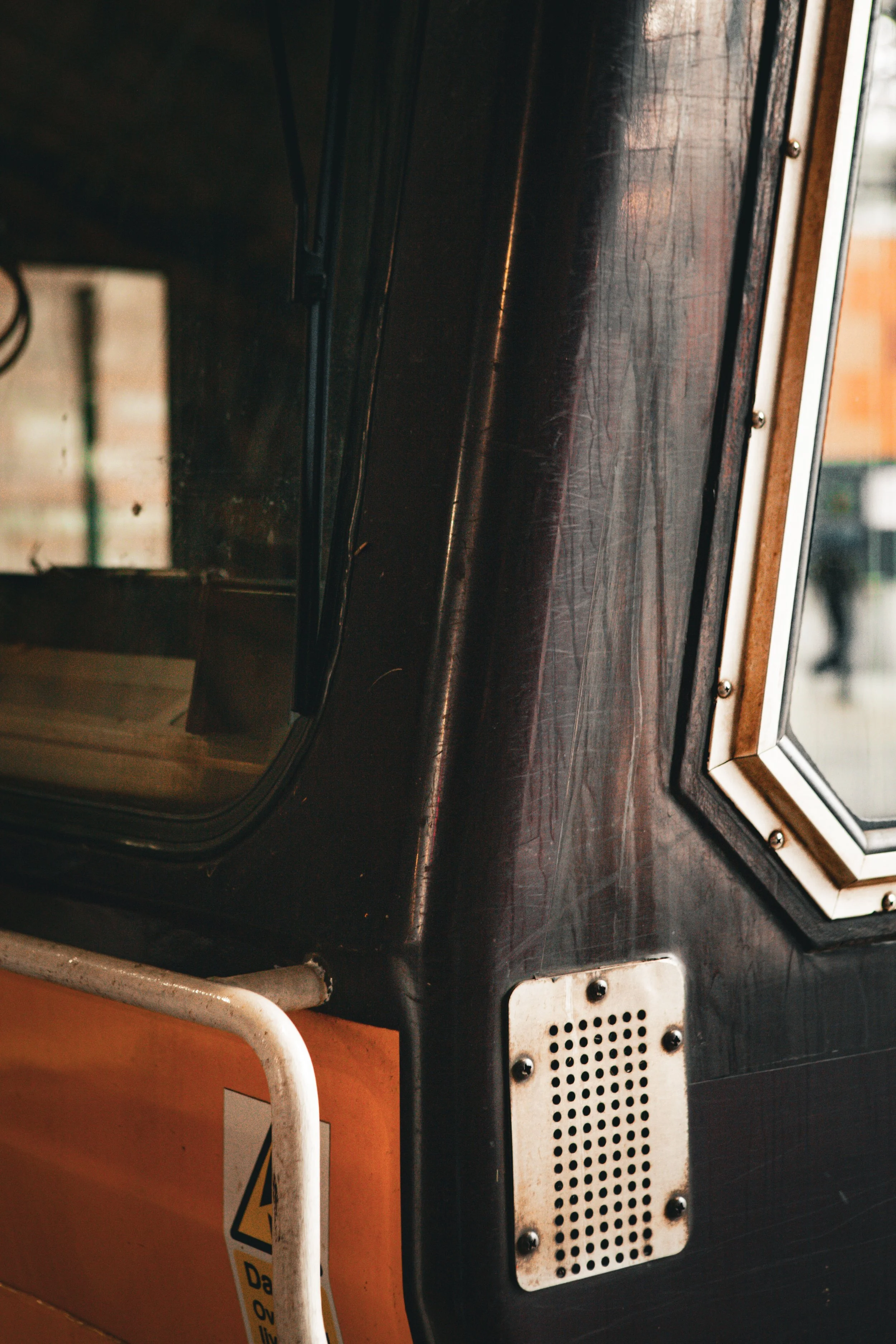 Close-up of an arcade game machine with a black surface, metal vent, and a partly visible orange-colored lower panel.