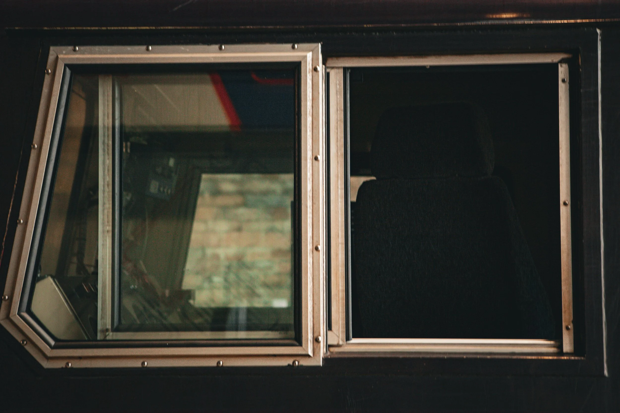 Close-up of a vintage TV with two screens, one with a glass front and the other open, black interior, and visible seat inside.