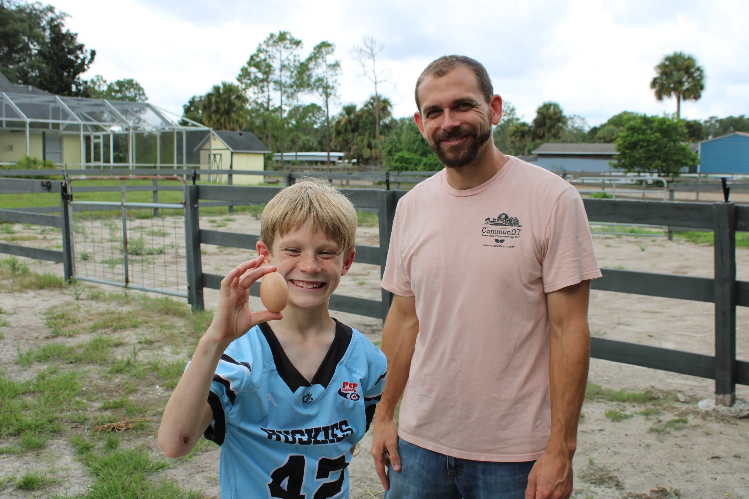 Boy holding chicken egg smiling next to OT