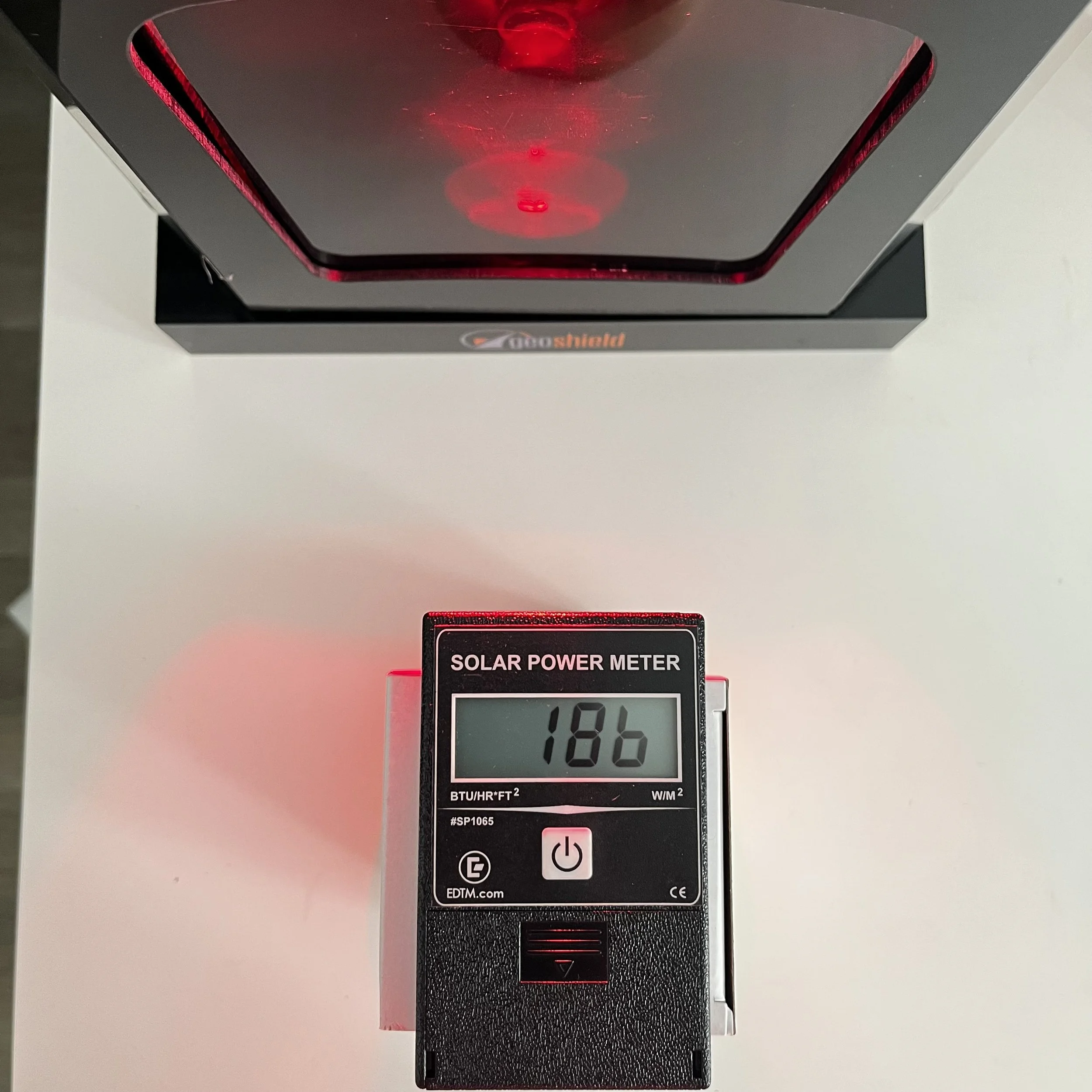 Solar power meter displaying 188 BTU/hr square feet, mounted on a device with a digital display and several buttons, with a red laser light projecting onto the ceiling.